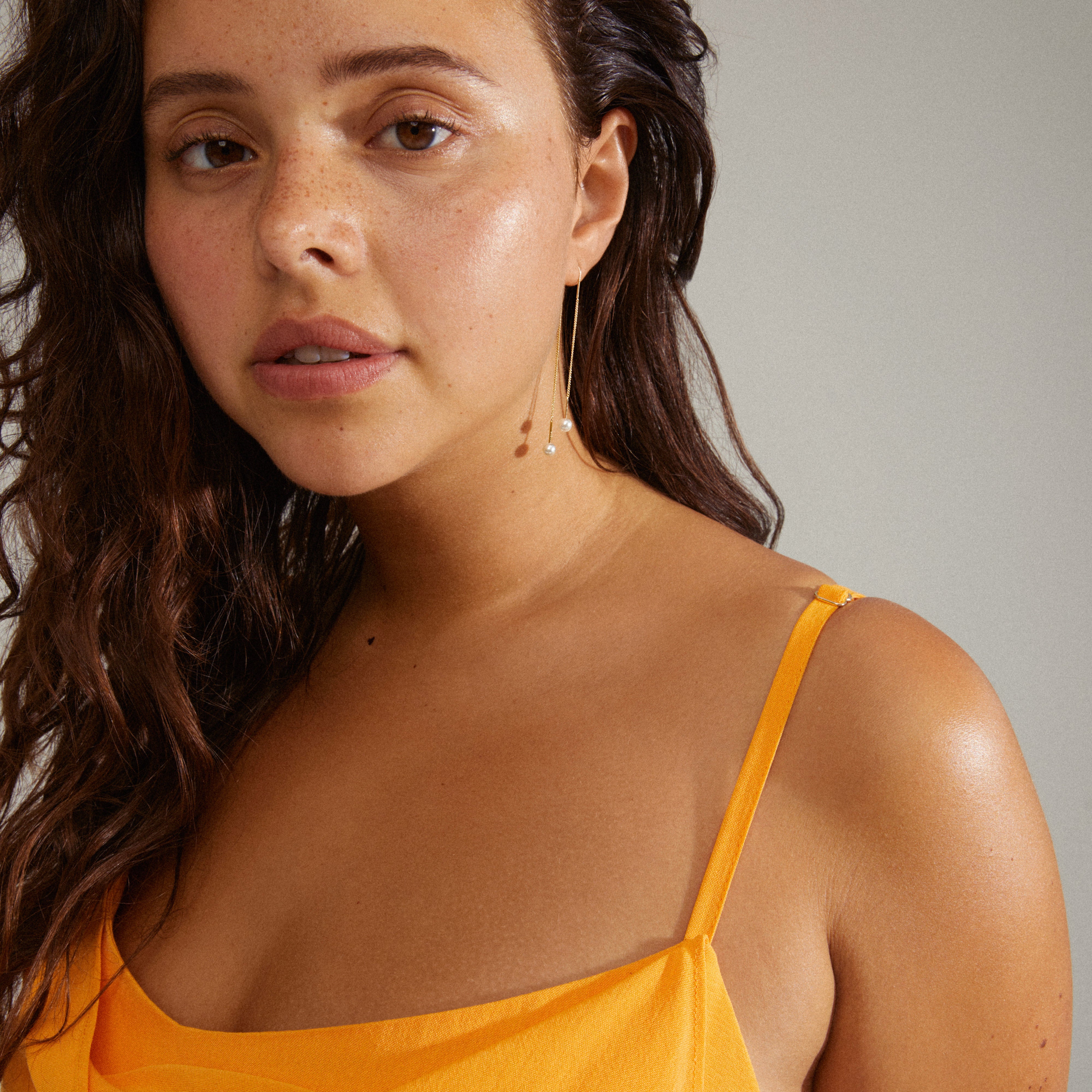 EUONIA pearl chain-earrings gold-plated adorn a woman, showcasing the elegant blend of removable pearls and chains for a versatile, classic look.