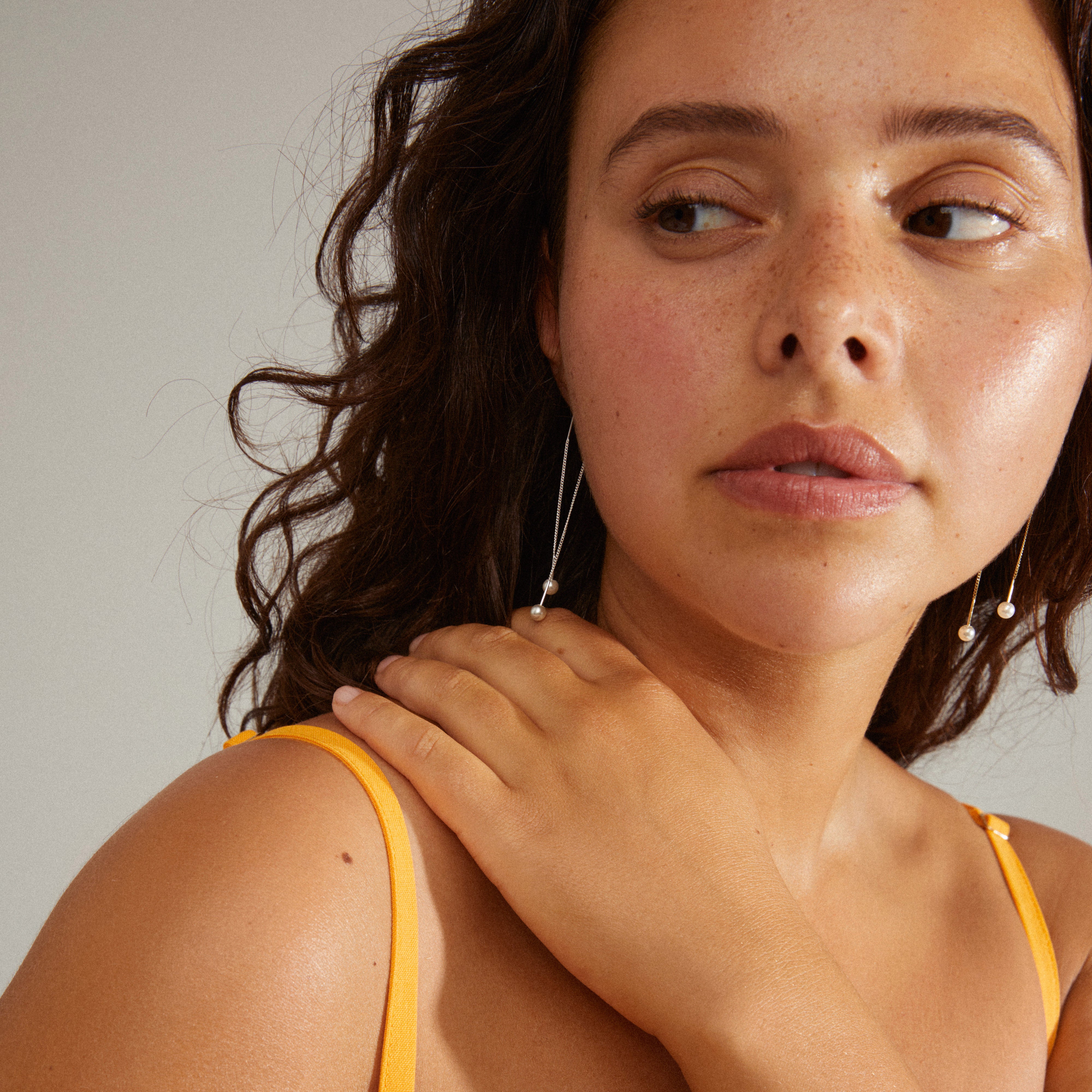 EUONIA pearl chain earrings, silver-plated, worn by a woman with her hand on her shoulder, showcasing the elegant, removable pearl design.