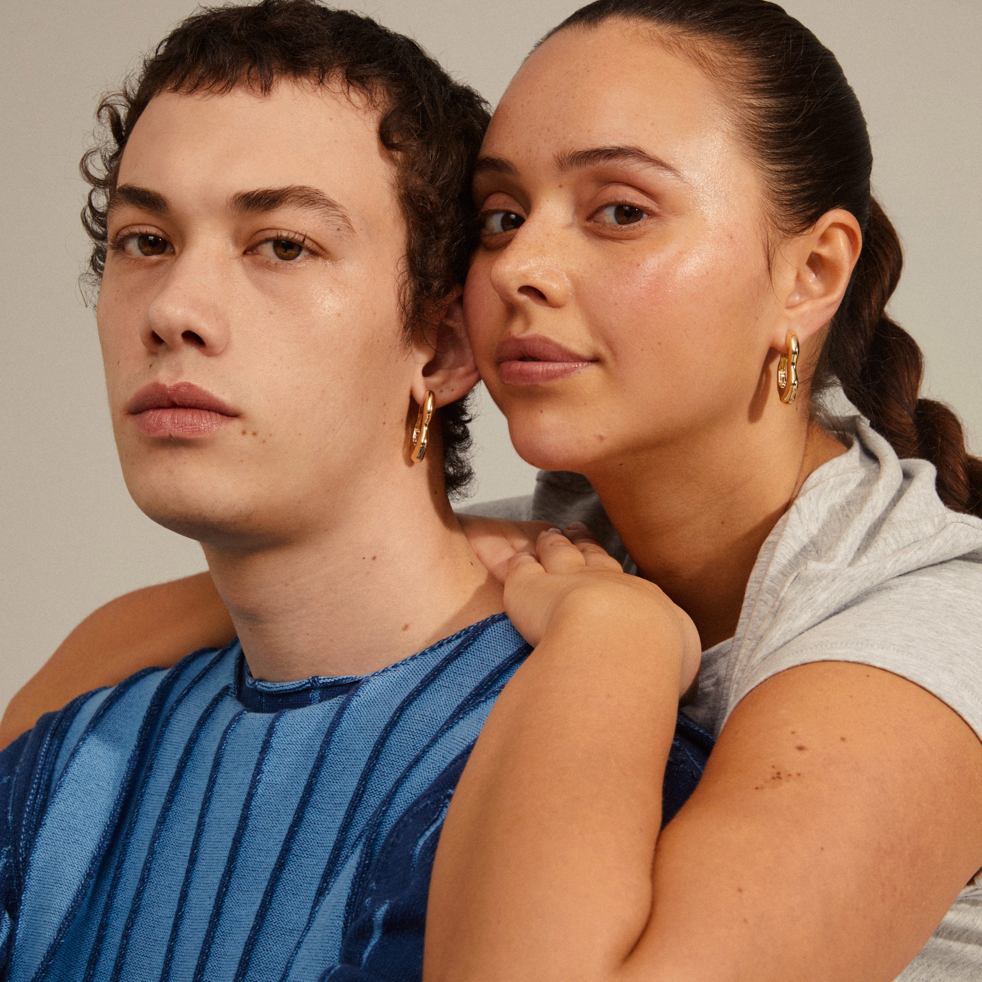 LOULIA wavy earrings gold-plated, showcased by a woman with braided hair, highlighting their oblong hoops and shiny finish, perfect for a trendy, eye-catching look.