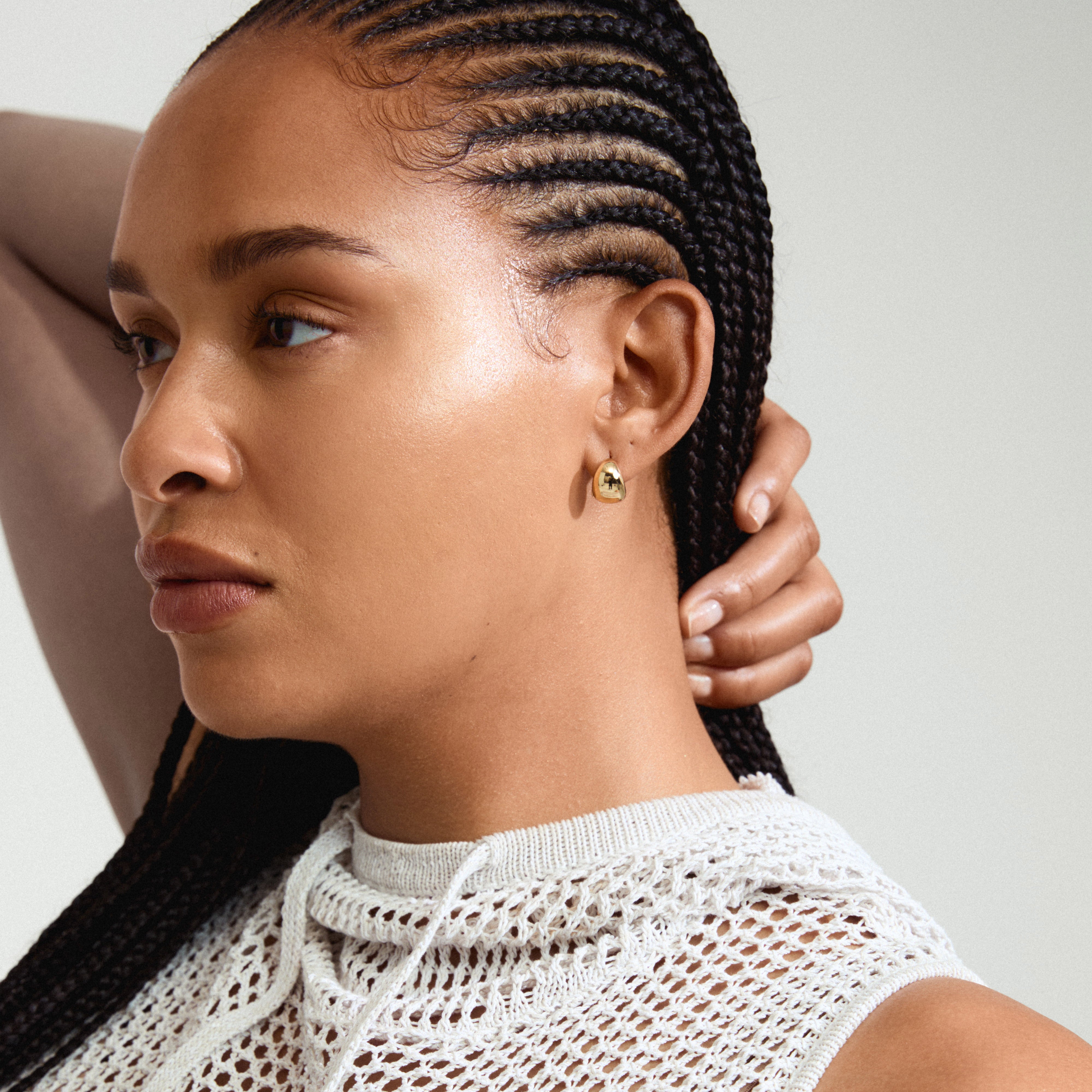 JUA earrings gold-plated in a chunky bubble dome design, worn by a woman with braided hair, showcasing a retro style and sustainable craftsmanship.