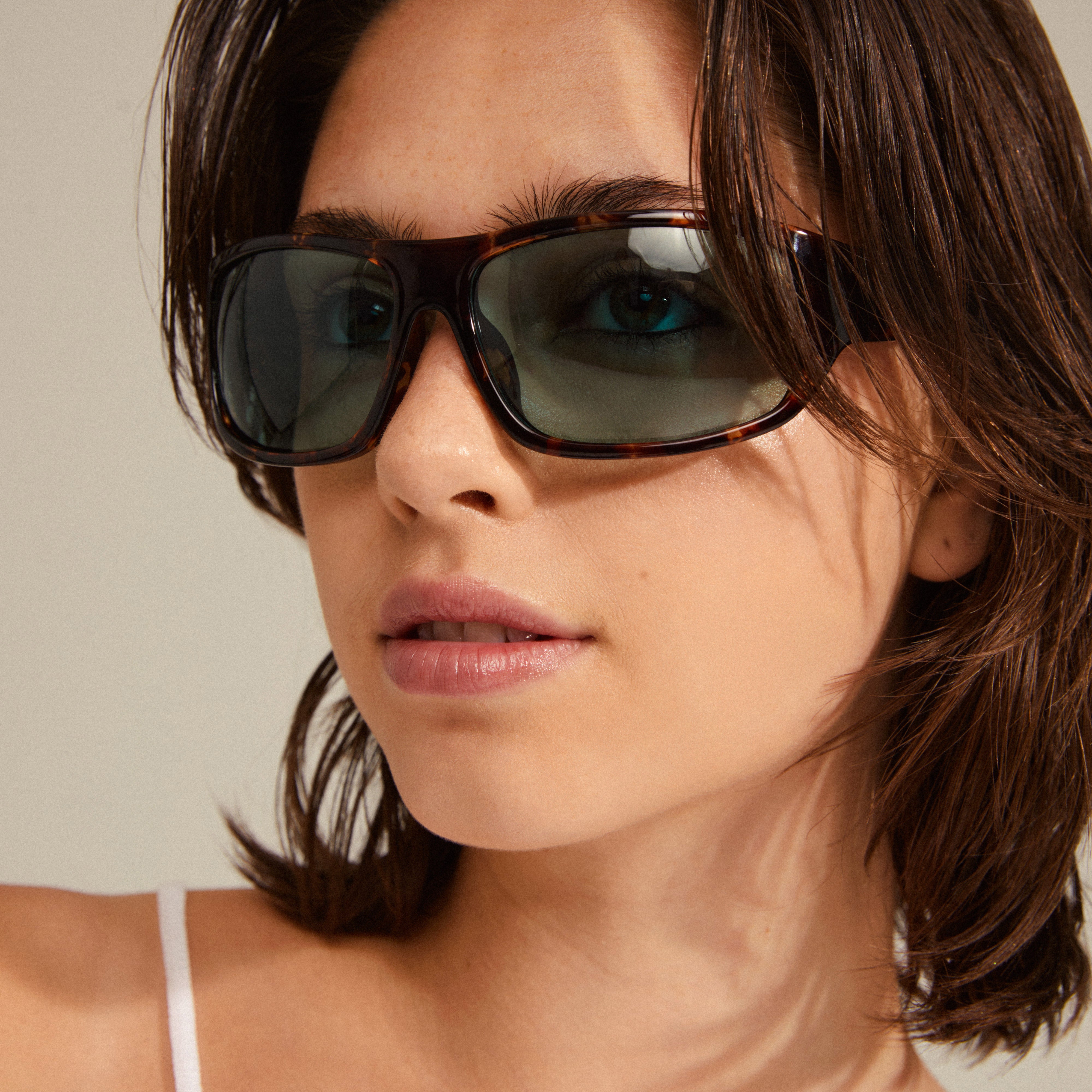 Woman wearing GERTRUD sunglasses in tortoise brown, showcasing their classic design with a trendy edge, featuring light blue lenses from Pilgrim.