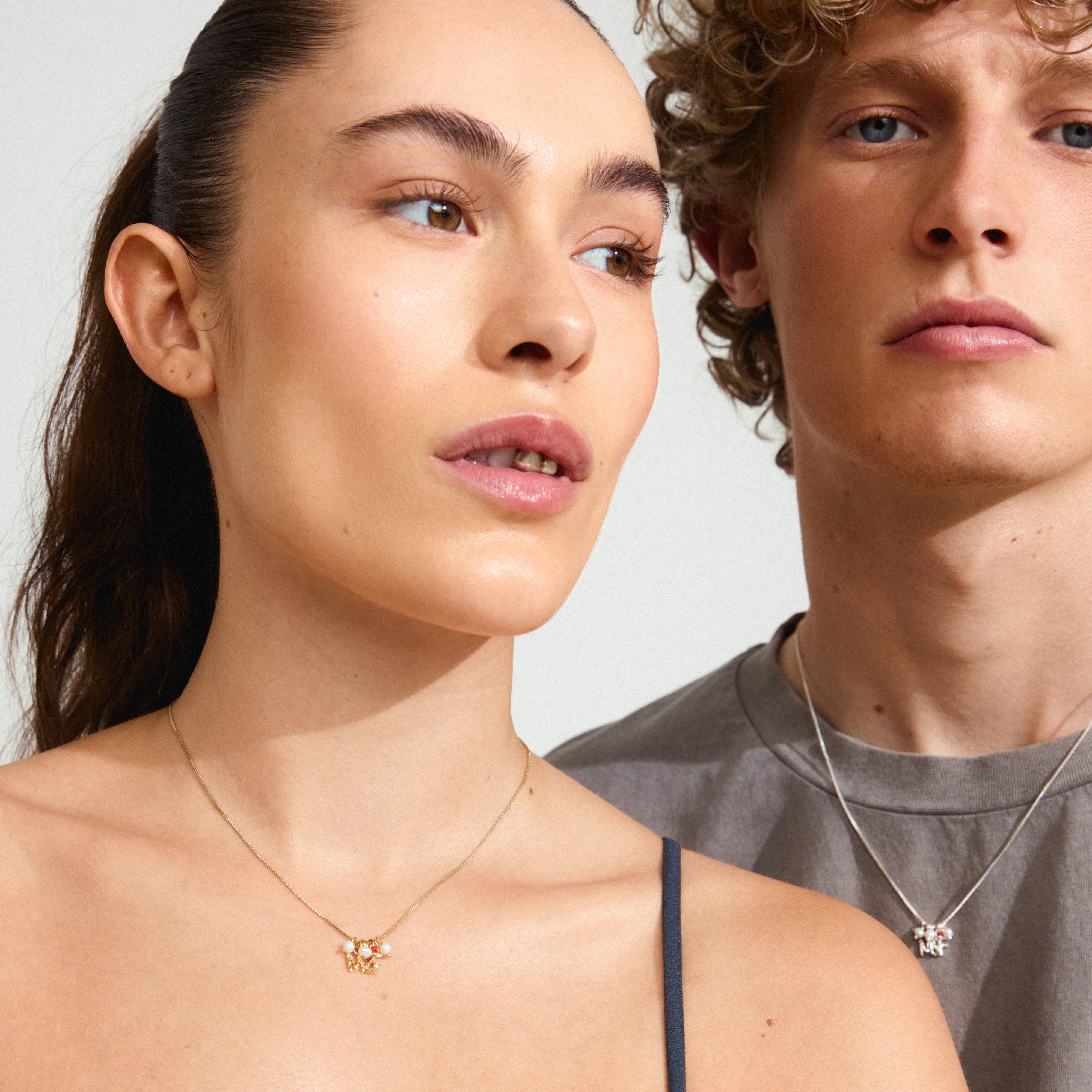MSF charity necklace gold-plated, featuring petit freshwater pearls and a red micro pearl, worn by a woman. Supports Doctors Without Borders.