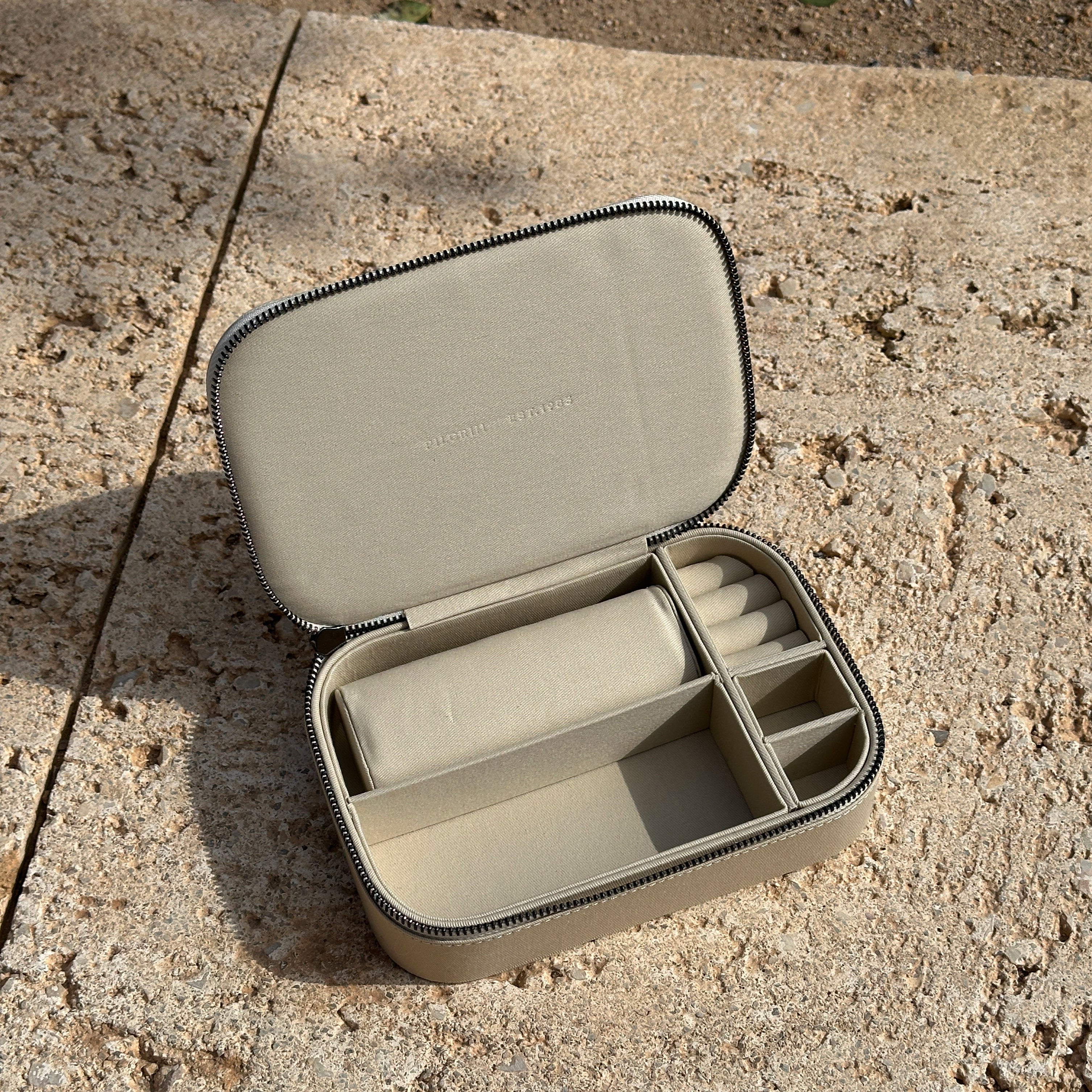 Jewellery box, Light Sand, Large: A close-up of a compact, cotton jewelry box with a zipper, featuring rows and compartments for organized storage of rings, earrings, and necklaces.