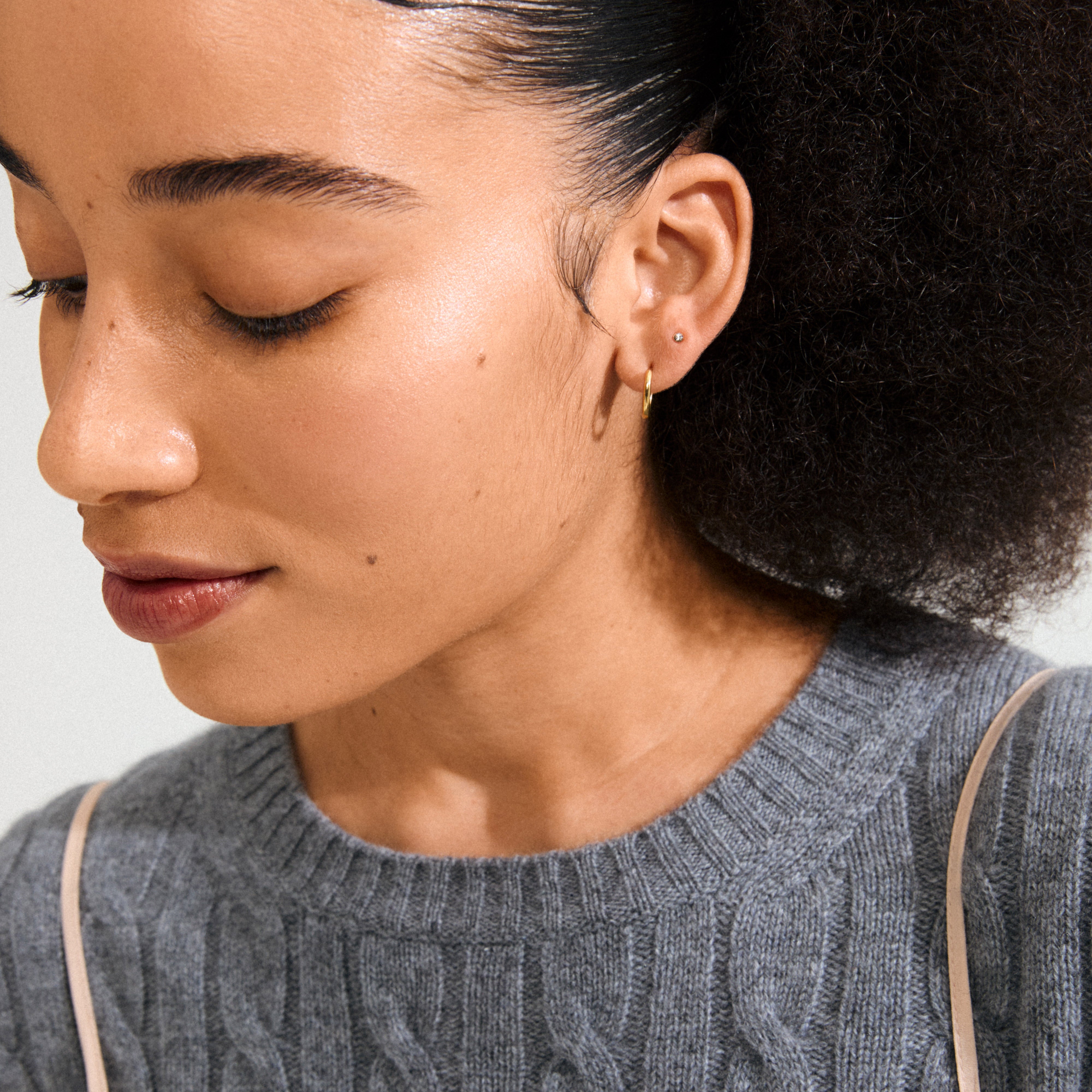 Young woman wearing HALO gift set earrings: a tiny stud and thin gold hoop, showcasing the 3-in-1 gold-plated, eco-friendly collection by Pilgrim.