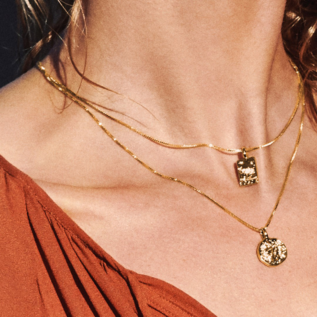 VALKYRIA coin necklace set features two gold-plated necklaces with Norse mythology-inspired serpent and raven charms, perfect for adding drama to any outfit.