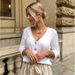 Woman wearing VALKYRIA coin necklace 2-in-1-set gold-plated, featuring Norse serpent and raven charms, standing outside a building.