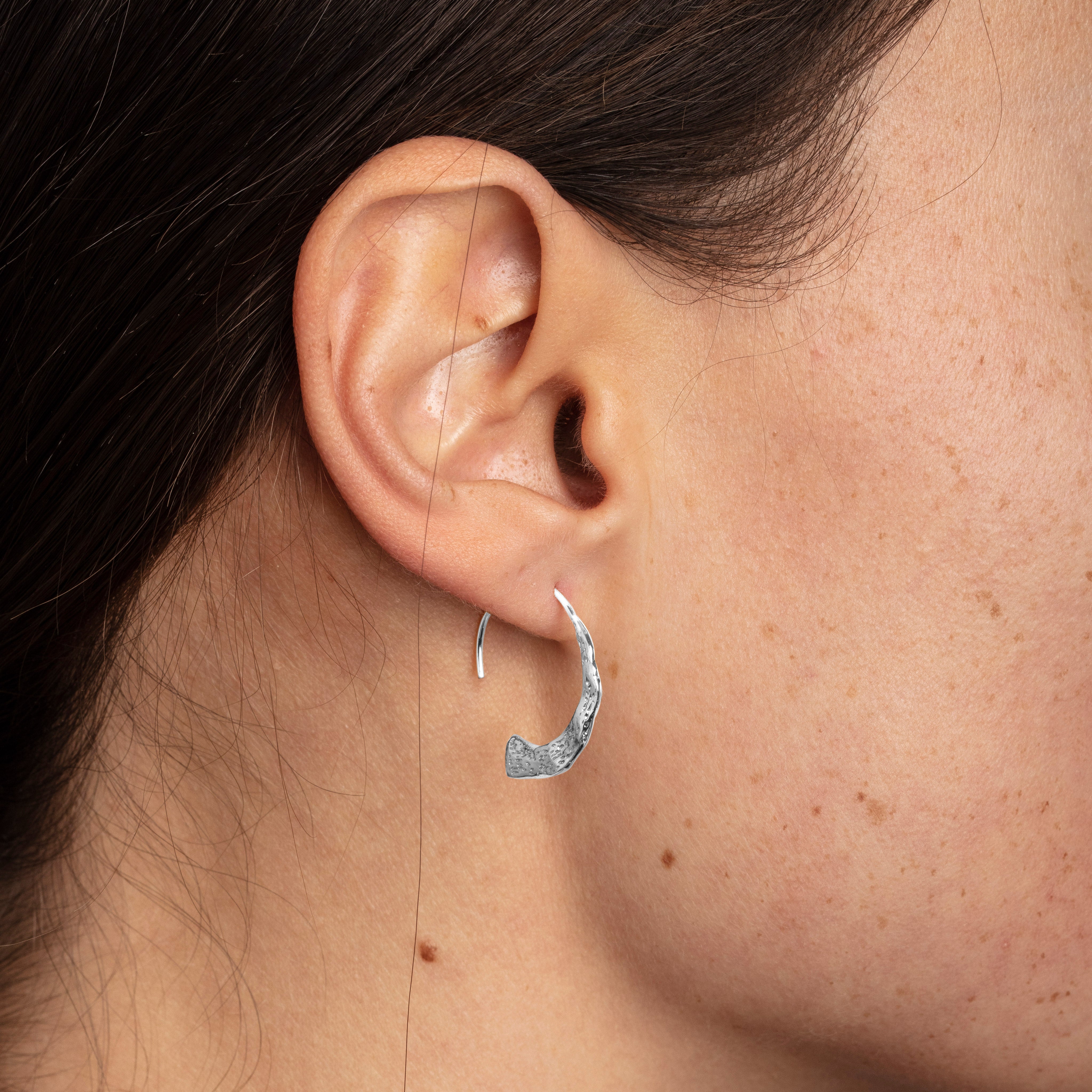 Close-up of VALKYRIA silver-plated hoop earrings, featuring a polished narrow ring and a wider hammered semicircle, highlighting their rustic Nordic-inspired design.