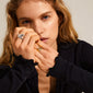Young woman wearing COMPASS organic-shaped, gold-plated ring, showcasing its chunky, hammered texture inspired by natural landscapes, highlighting its statement and adventurous style.