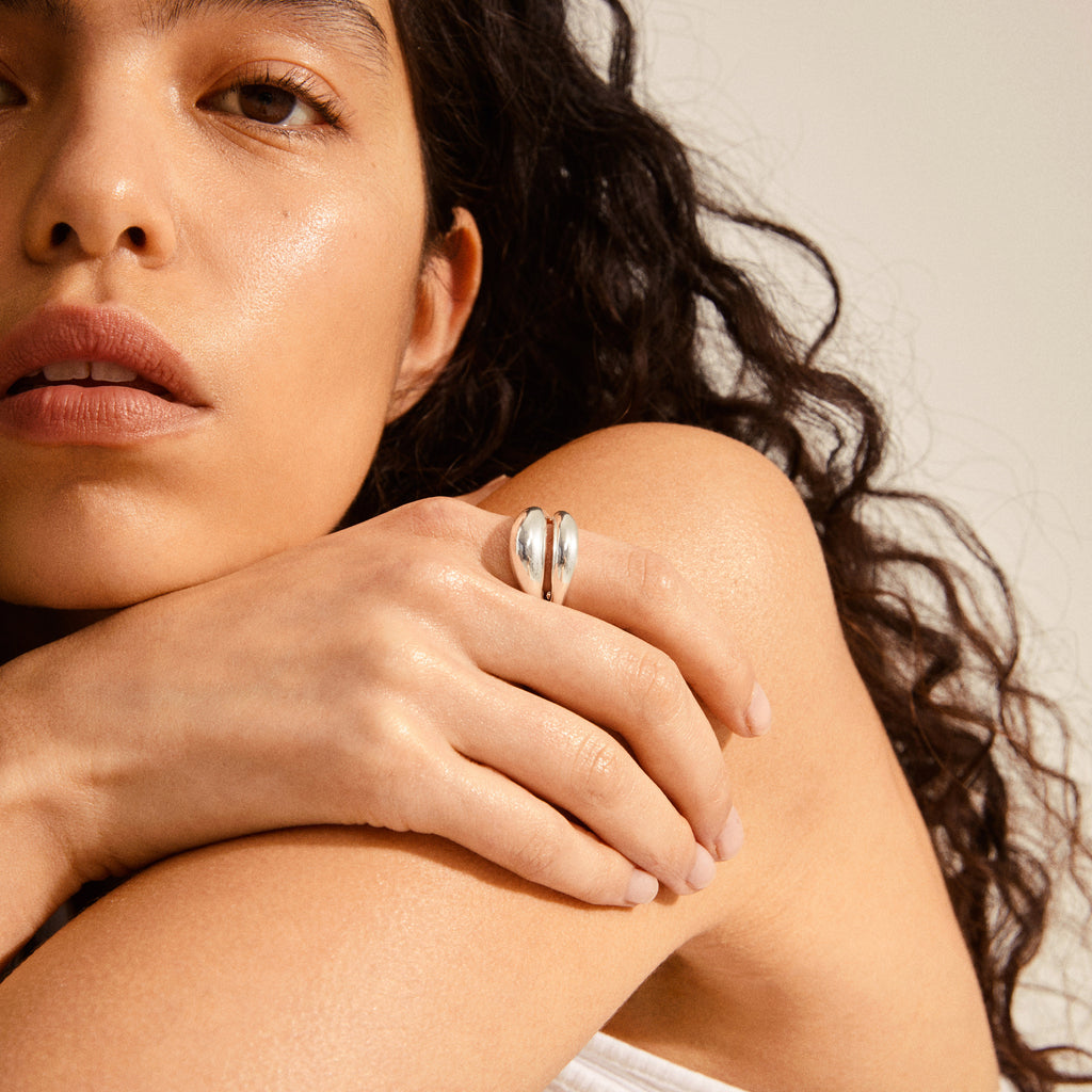 RECONNECT chunky statement ring silver-plated showcased on a person's hand resting on their shoulder, featuring polished, organically curved bands reflecting Pilgrim's timeless and trendy design ethos.