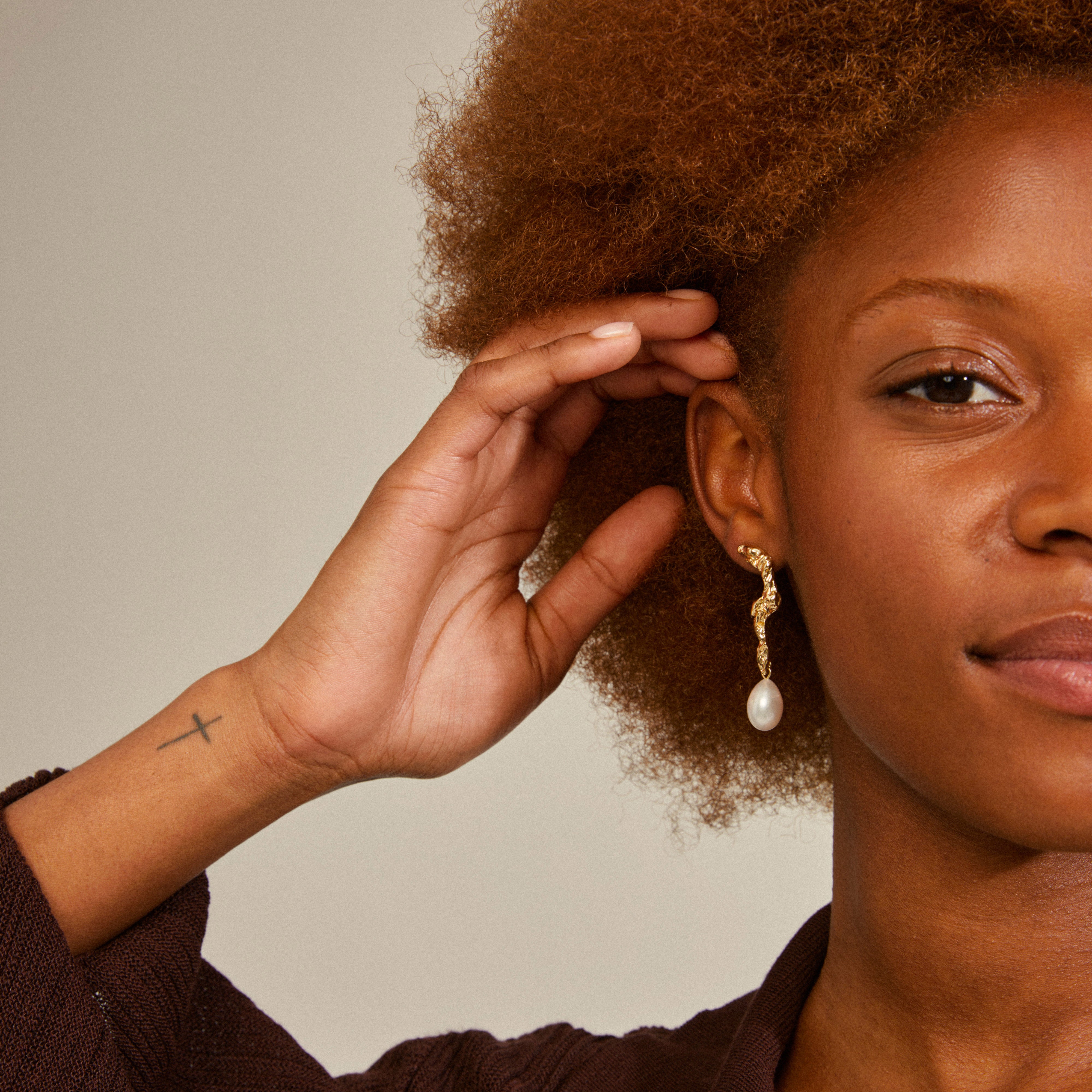 Woman wearing Pilgrim's MOON earrings, featuring gold-plated asymmetrical design with a large freshwater pearl pendant, showcasing a creative and luxurious boho style.