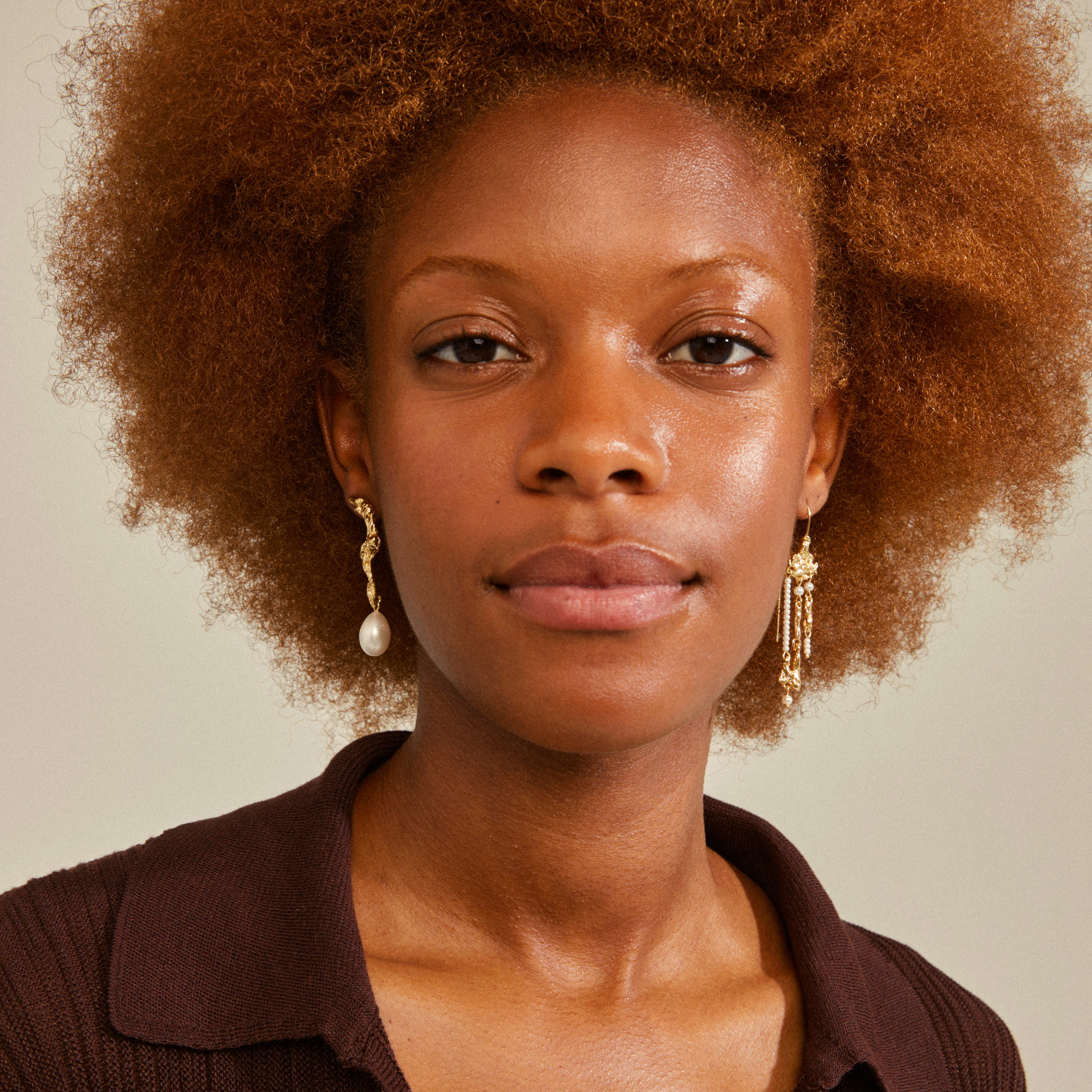 MOON earrings gold-plated; asymmetrical design with organic shapes and large freshwater pearl pendants, worn by a red-haired woman with earrings.
