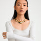 Young woman wearing Pilgrim's FREE statement necklace, featuring bold, gold-plated asymmetrical nodules, embodying a standout, luxurious style. Perfect for spotlight moments.