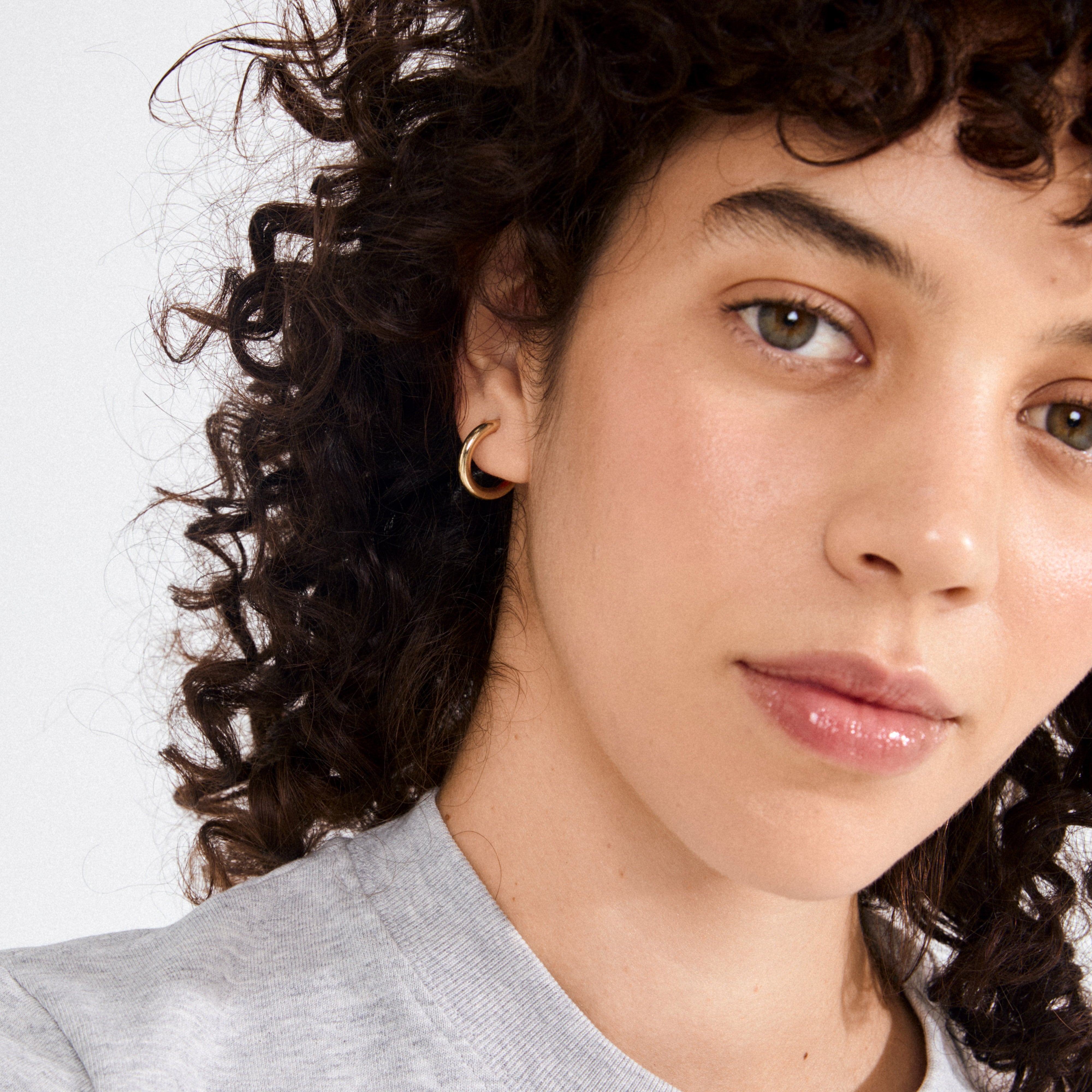 DOLAG earrings gold-plated: A young person models stylish gold-plated chunky half hoops, showcasing a bold, timeless design crafted from 98% recycled materials.