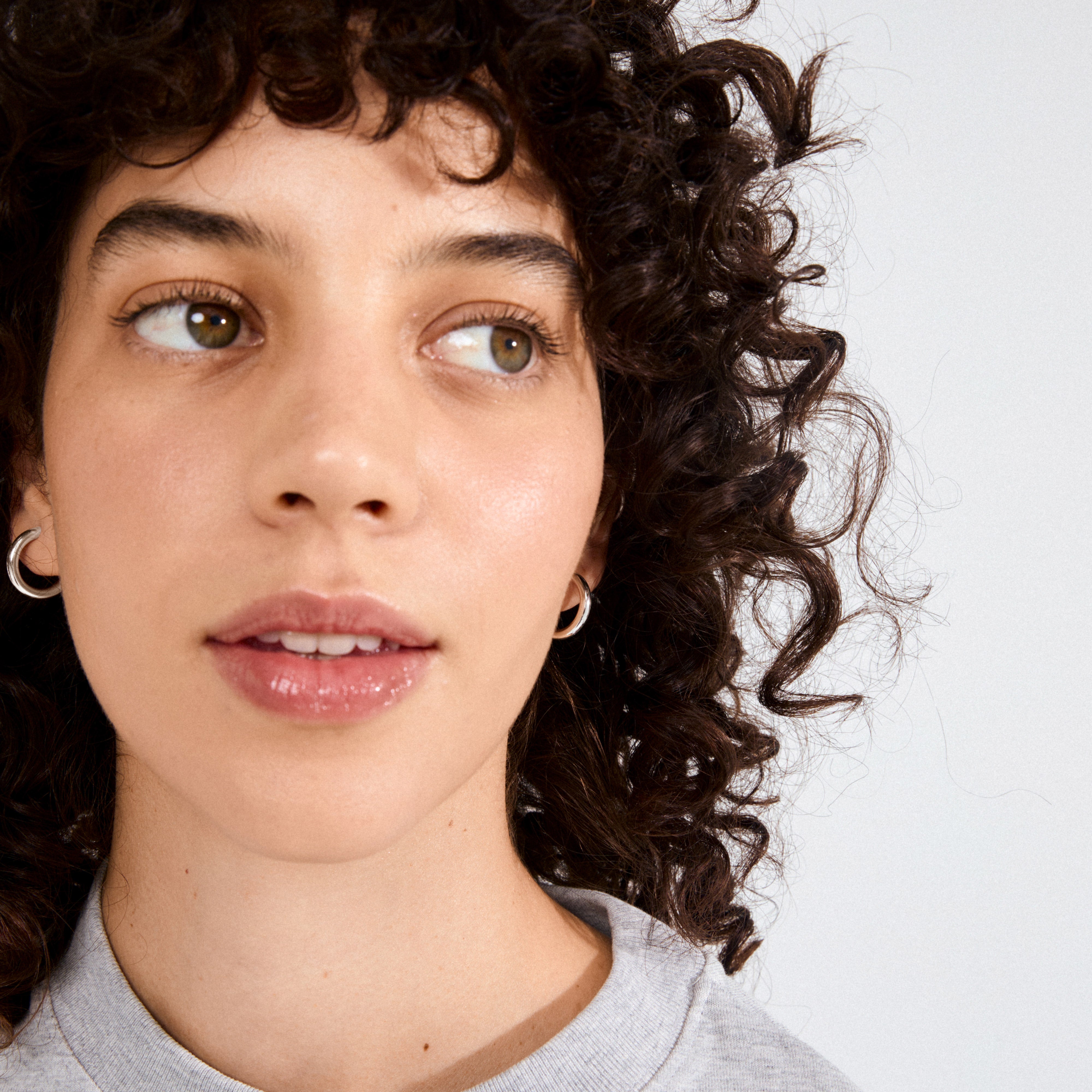 Young person wearing DOLAG earrings silver-plated, showcasing bold, chunky half hoops crafted from 98% recycled materials, embodying effortless, timeless style.