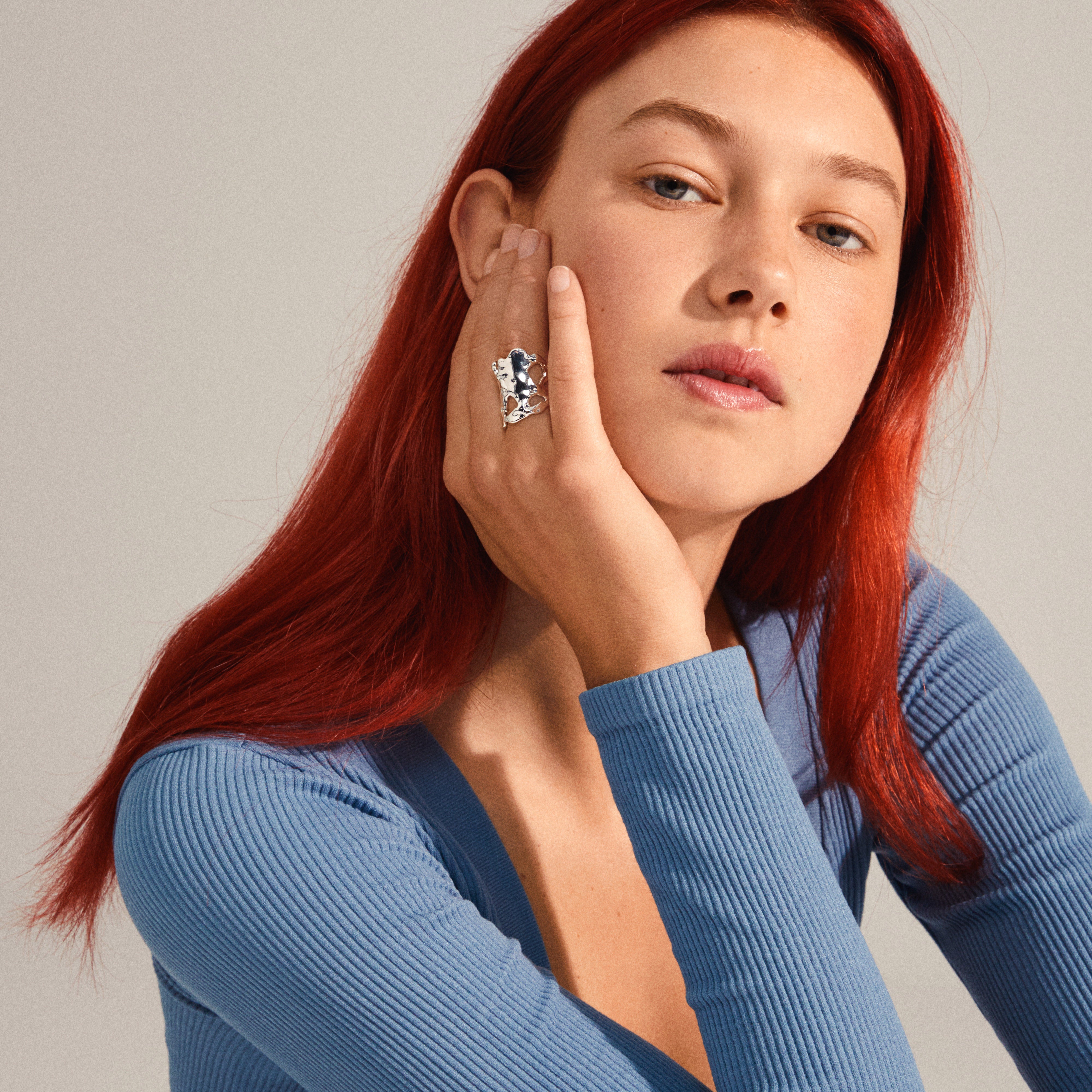 Young person showcasing Pilgrim's HAPPY organic-shaped, silver-plated ring with a sculptural design, highlighting its raw, handcrafted feel against a neutral background.