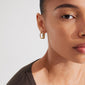 Close-up of a woman wearing Pilgrim's STAR gold-plated hoop earrings adorned with sparkling Preciosa crystals, showcasing their elegant oval shape and stylish design.