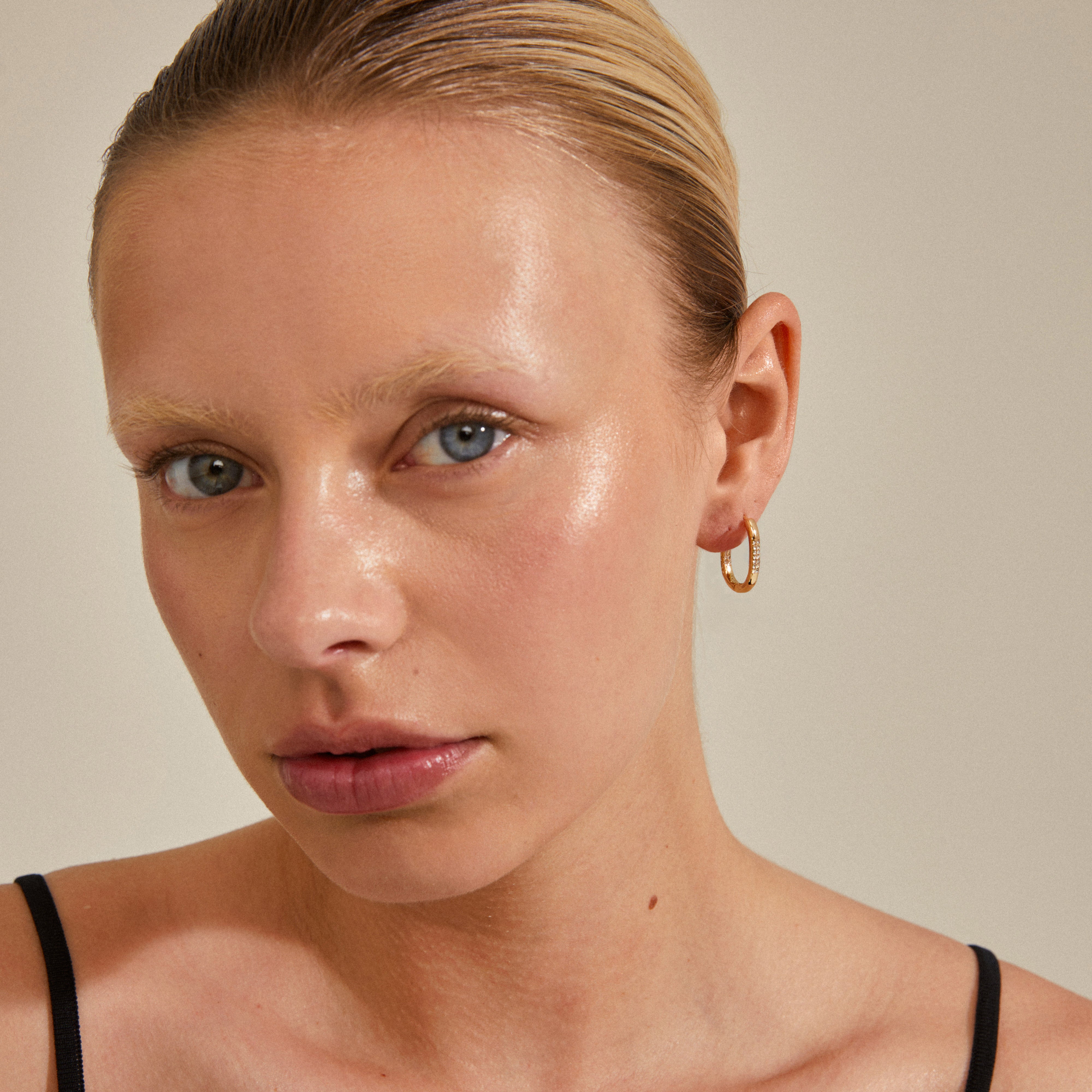 Close-up of a woman wearing Pilgrim's STAR collection gold-plated hoops, featuring an elegant oval shape adorned with Preciosa crystals.