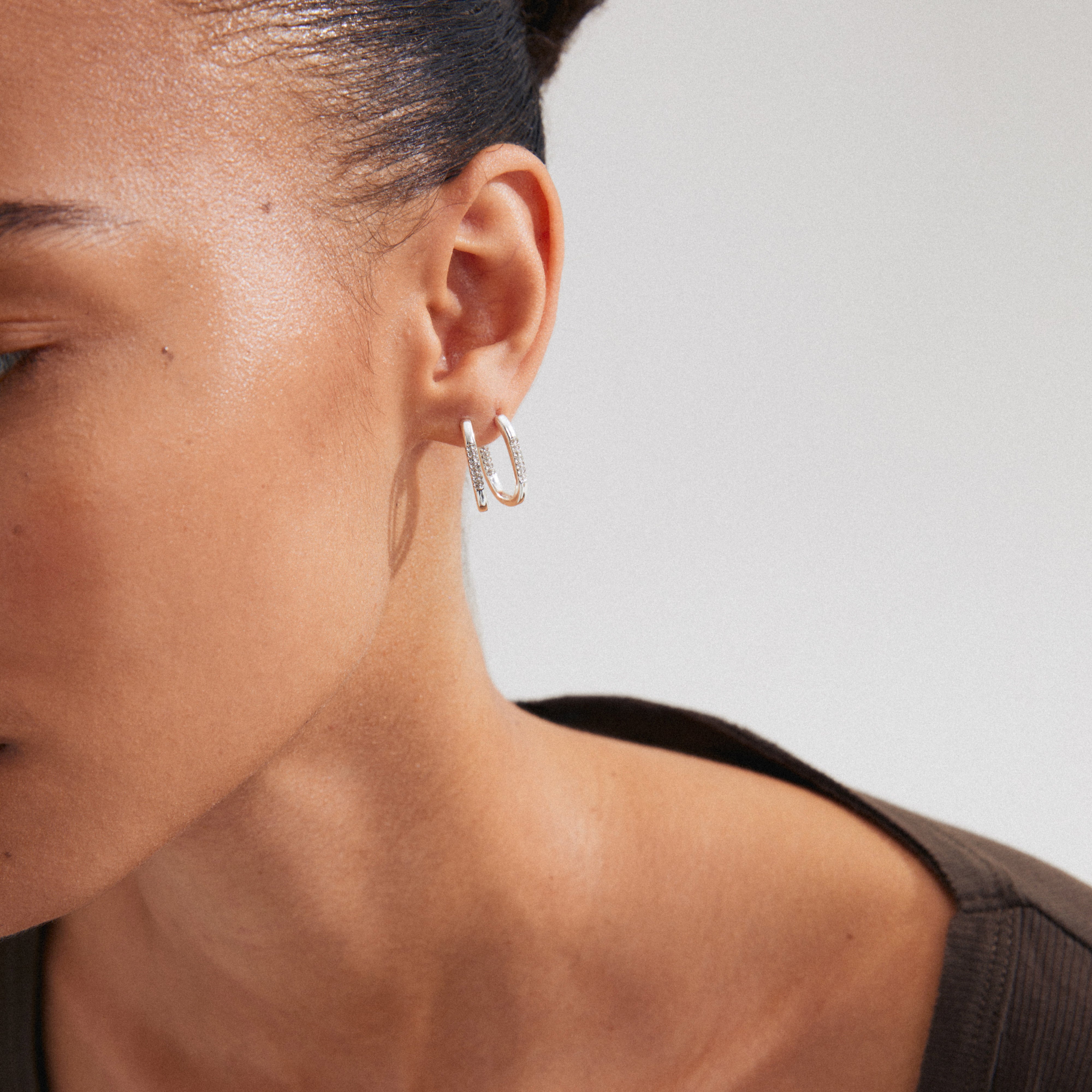 Close-up of a woman's ear showcasing Pilgrim's STAR hoops, silver-plated, with sparkling Preciosa crystals and an easy click clasp design.