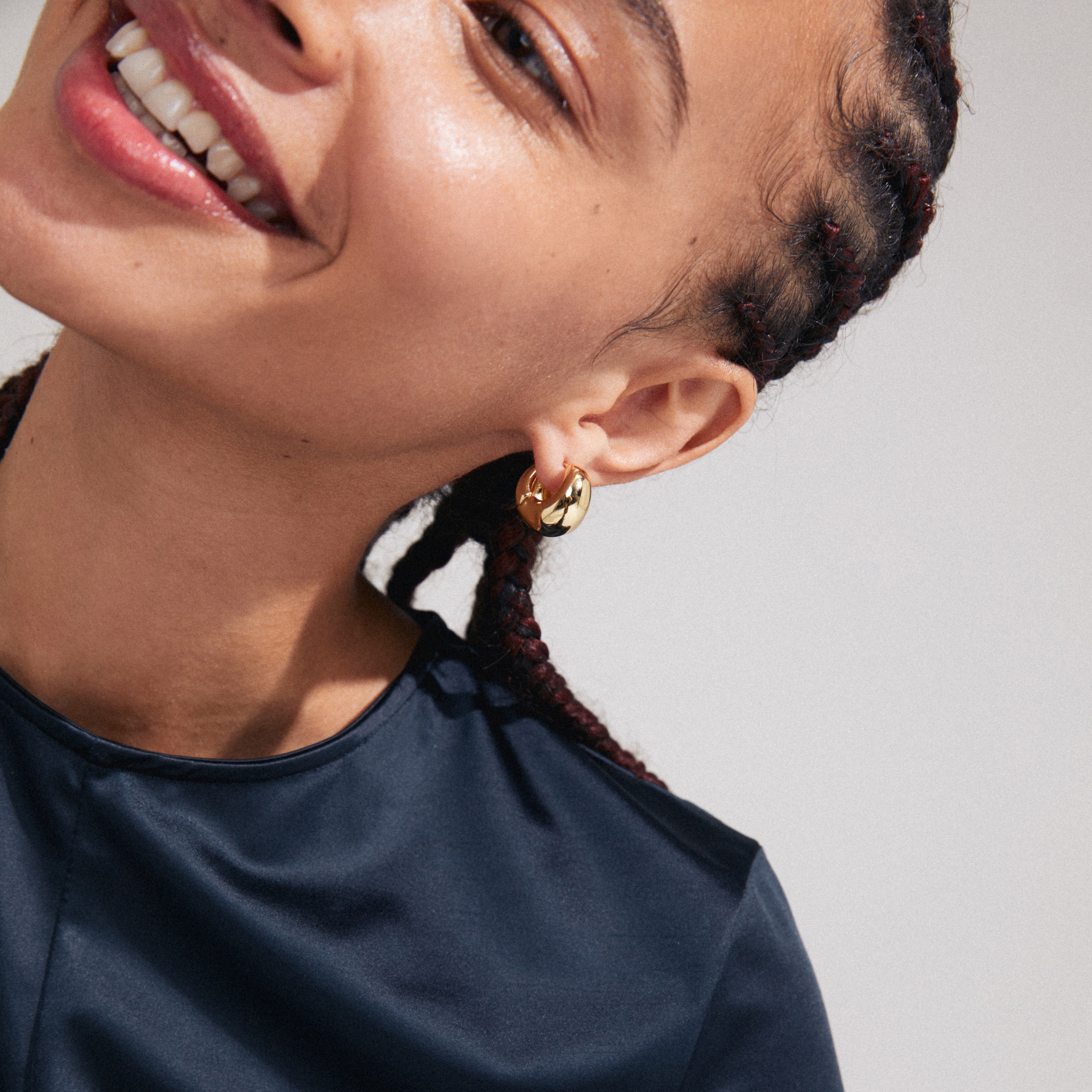Woman wearing Pilgrim's LIGHT chunky gold-plated earrings, showcasing the earrings' unique wavy design and Scandinavian-inspired style.