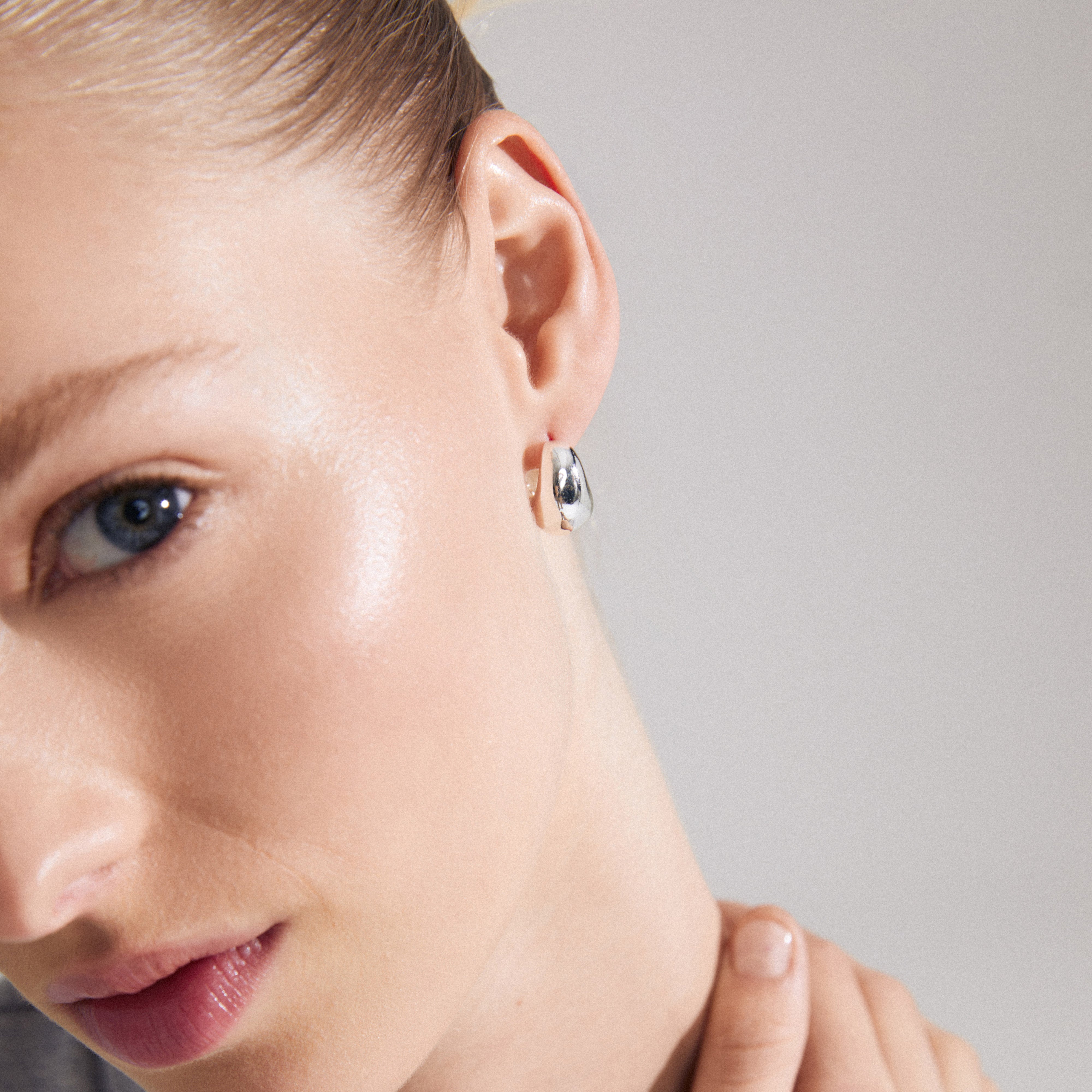 Close-up of a woman's face showcasing Pilgrim's LIGHT chunky silver-plated earrings with unique wavy design and easy click clasps.