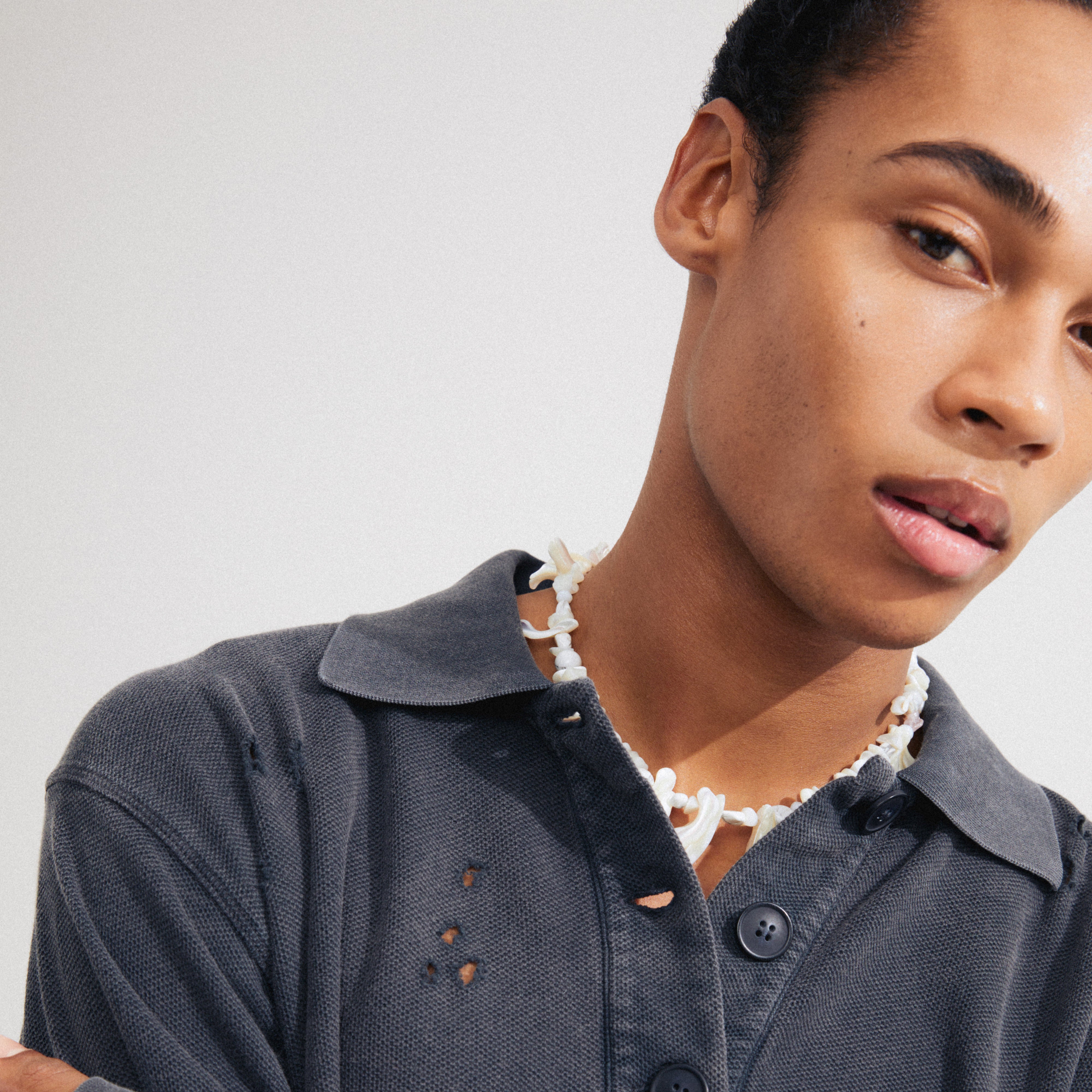 Man wearing Pilgrim's LIGHT seashell necklace in white/silver-plated, featuring irregular mother-of-pearl and semi-precious stones, conveying a boho luxe feel.