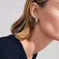 Profile view of a person wearing Pilgrim's FOCUS crystal earrings, showcasing a teardrop gold hoop with pavé-set sparkling stones, embodying minimalist Scandinavian elegance.