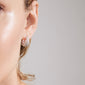 Close-up of a person's ear wearing Pilgrim's FOCUS crystal earrings, silver-plated with sparkling Preciosa crystals, showcasing a chunky, sophisticated design.