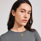 Close-up of a woman's neck wearing the BELIEVE necklace gold-plated by Pilgrim, featuring a slim chain and fluid pendant.
