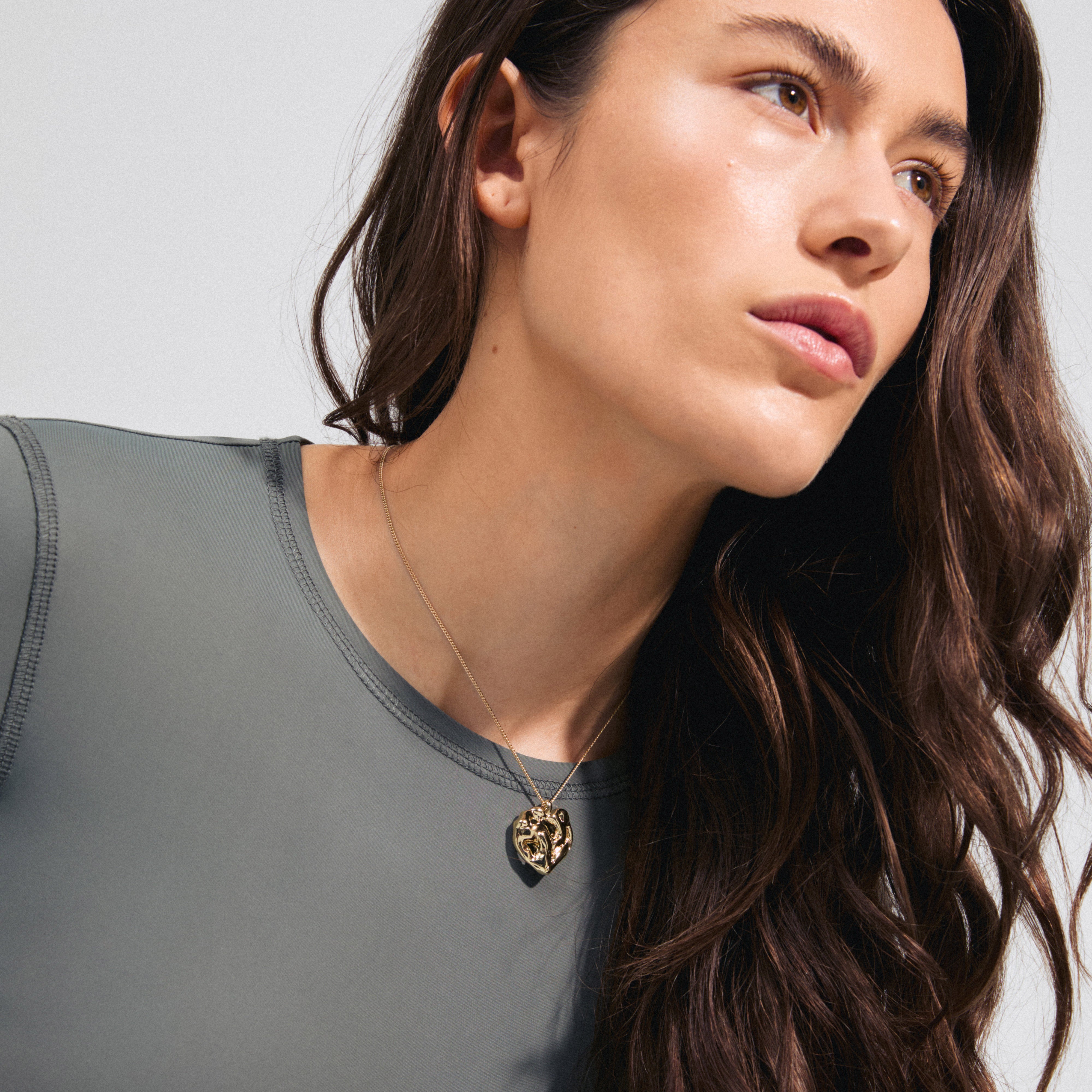 BELIEVE necklace gold-plated with a fluid organic pendant, worn by a woman, showcasing its adjustable 70 cm chain. Perfect for adding a personal touch.