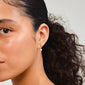 Close-up of a woman wearing Pilgrim's STARLIGHT gold-plated pearl earrings, featuring organic shapes and freshwater pearls, highlighting their elegant and versatile design.