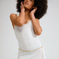 Person wearing a white tank-dress with Pilgrim's INSTANT gold-plated multi-chain belt, featuring flat, rectangular links, adding a chic, handcrafted touch.
