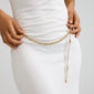 Person wearing a white ribbed dress, showcasing Pilgrim's INSTANT gold-plated multi-chain belt with flat, rectangular links and raw, handcrafted texture.