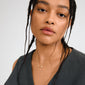 Woman wearing Pilgrim's INSTANT necklace, a gold-plated 2-in-1 set, featuring layered chains with an oval pendant adorned with sparkling crystals, exemplifying edgy elegance.