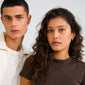 Two young adults wear Pilgrim's INSTANT earrings 2-in-1 set, showcasing gold-plated hoops and studs with Preciosa crystals, embodying a chic, urban vibe.