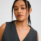 Young person wears Pilgrim's INSTANT necklace, featuring silver-plated, uneven rectangular links, exuding an artisanal charm, paired with a V-neck charcoal-gray top.