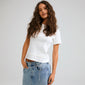 Young woman wearing INSTANT body jewellery silver-plated chain belt, styled with a white t-shirt and jeans, showcasing Pilgrim's raw, handcrafted urban look.