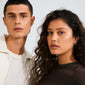Two young adults showcase Pilgrim's INSTANT earrings 2-in-1 set, silver-plated, featuring small studs and oval hoops with shimmering crystals, perfect for a stylish, everyday ear-stacking look.