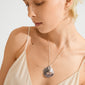 Person wearing Pilgrim's SPARKLE necklace, featuring a silver-plated chain with a large, wavy pendant, highlighting its handcrafted, Scandinavian design against their skin.