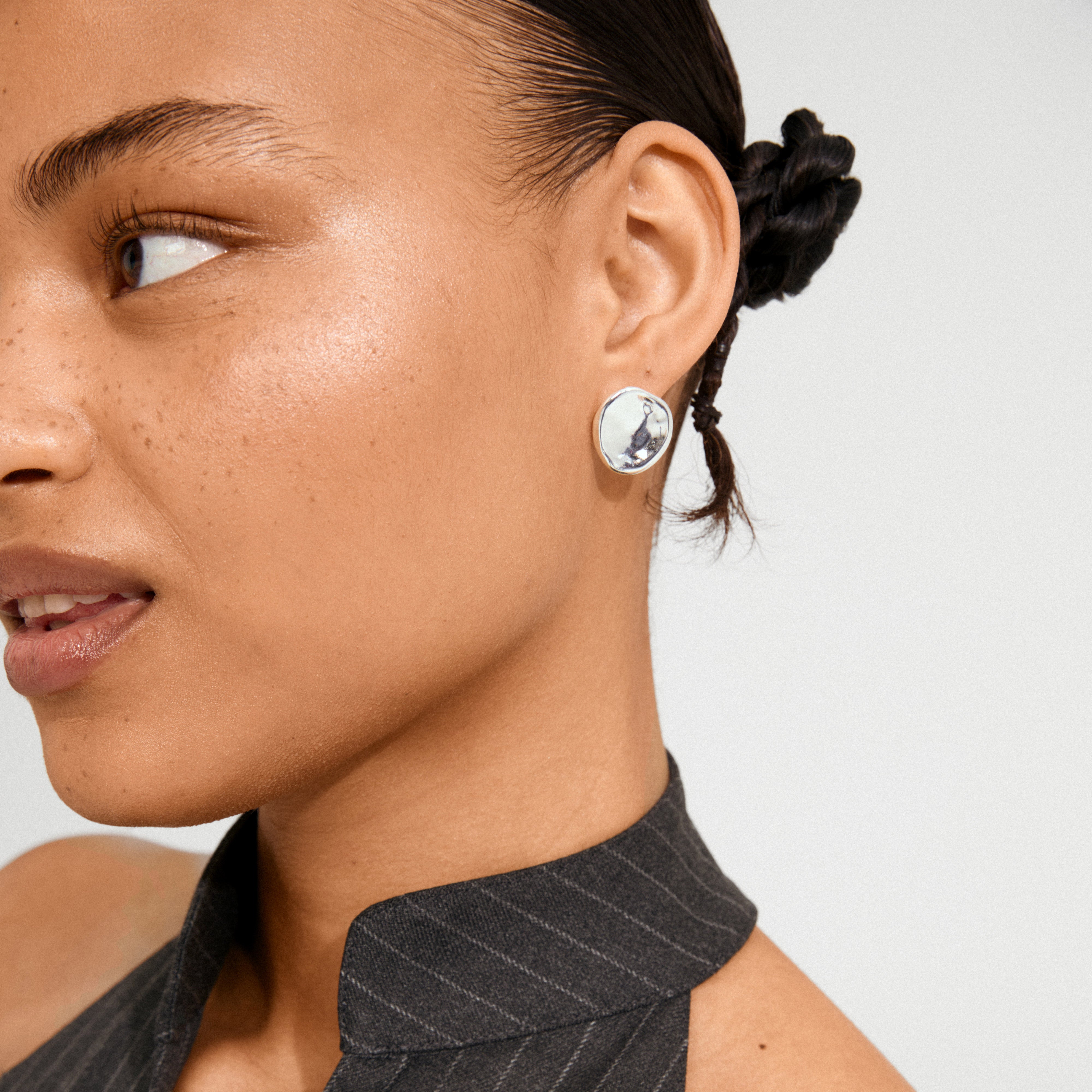 Young woman wears SPARKLE earrings silver-plated by Pilgrim, featuring a hammered finish that reflects light, conveying timeless appeal and eco-conscious elegance.