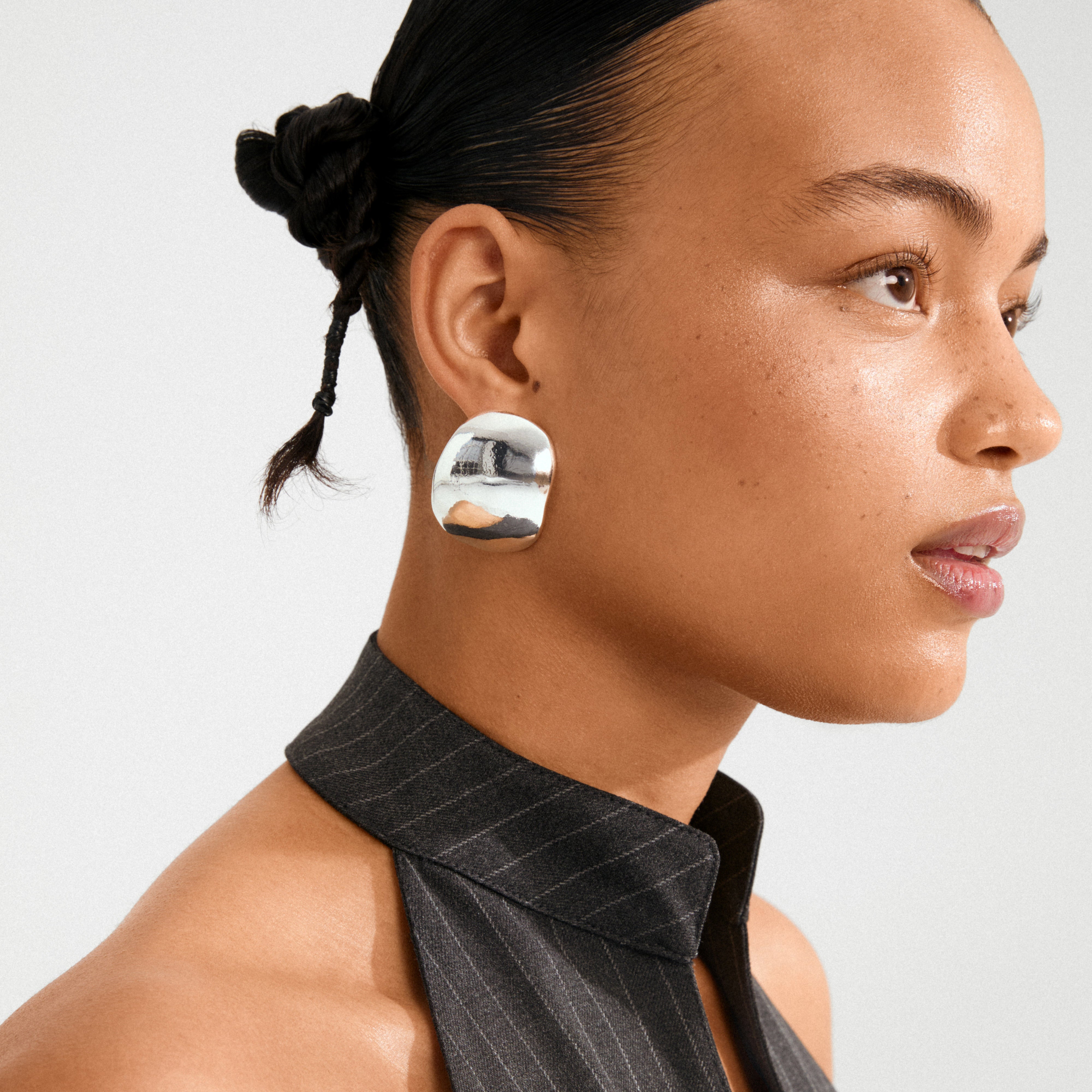 Close-up of a young woman wearing SPARKLE earrings silver-plated, showcasing their bold, sculptural design and vintage vibe, highlighting Pilgrim's trendy and sustainable jewellery.