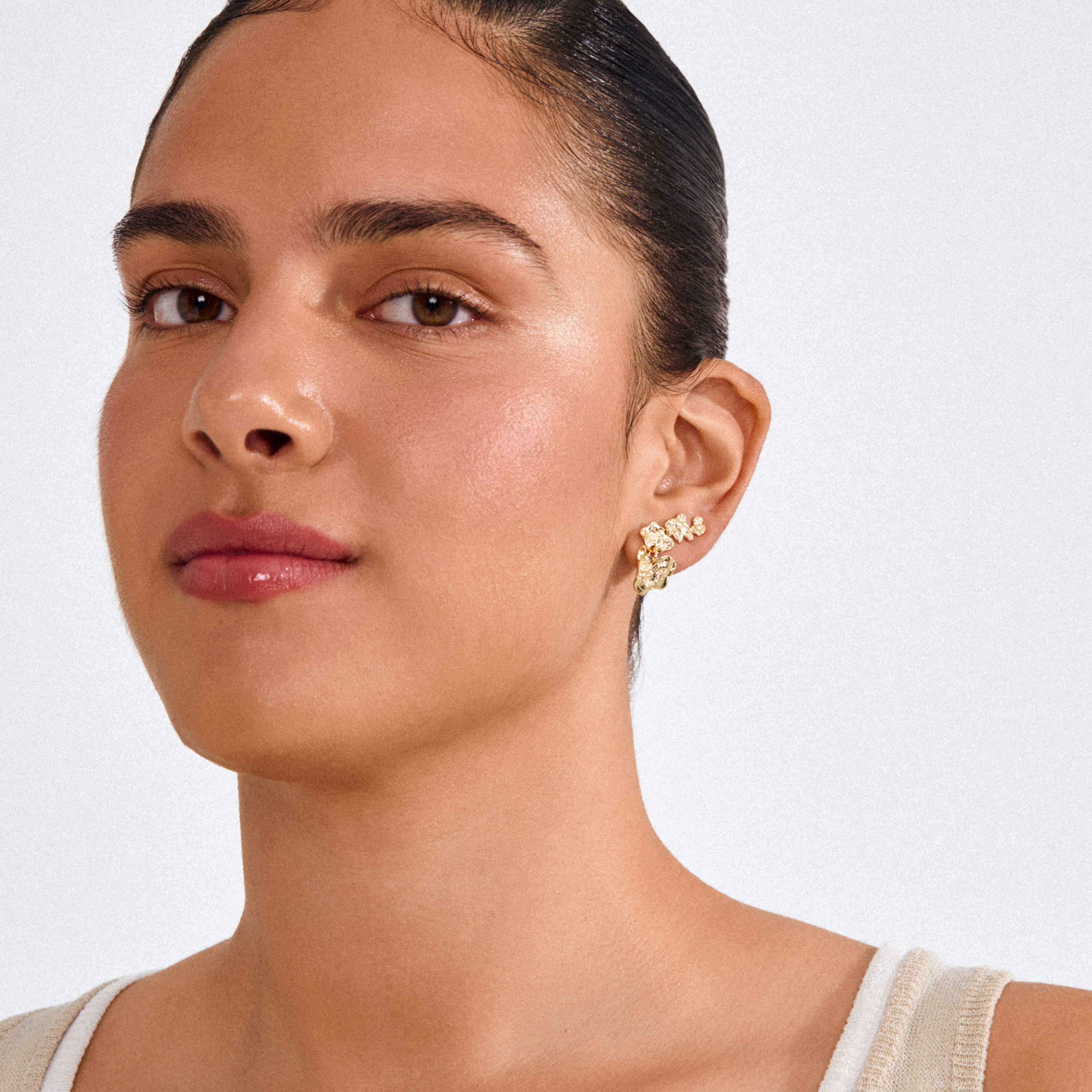 Close-up of a person wearing HORIZON earrings gold plated, showcasing a curved, clustered design. Ideal for trendy ear curation with six mix-and-match pieces.