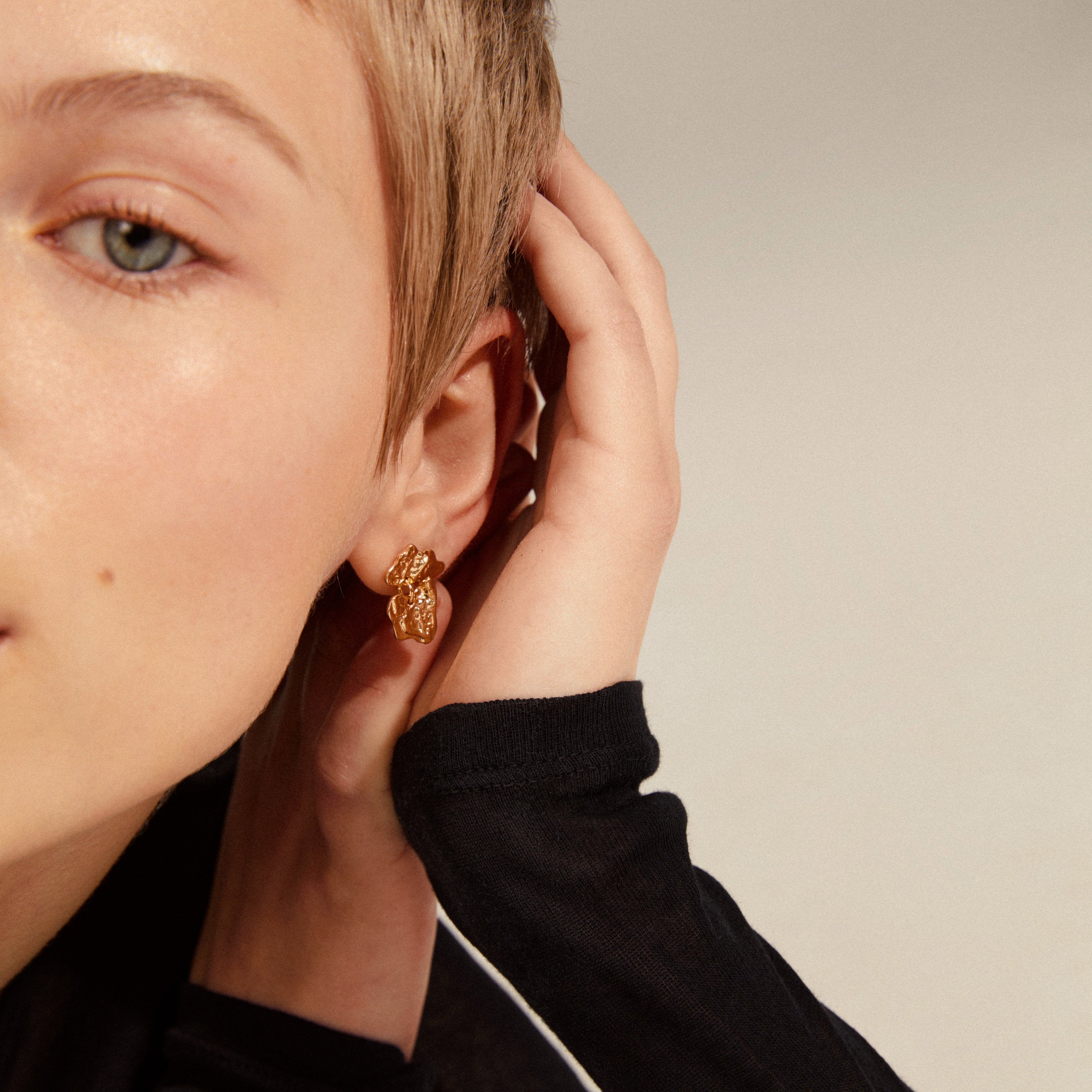 Close-up of a woman's ear showcasing HORIZON gold-plated earring from Pilgrim, emphasizing trendy ear curation and timeless Scandinavian design.