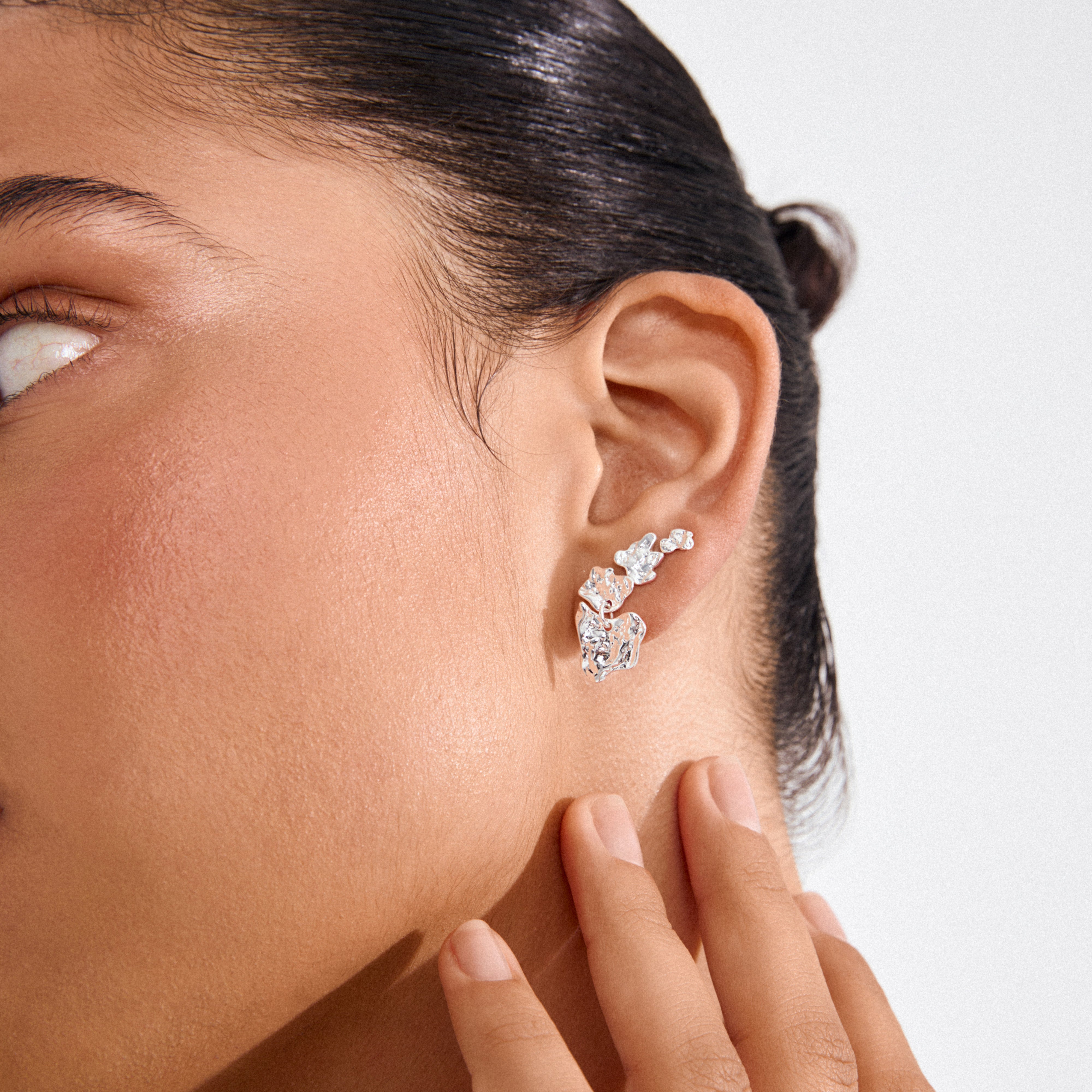 Close-up of an ear wearing a sculptural silver-plated HORIZON earring by Pilgrim, elegantly climbing the earlobe, reflecting Scandinavian craftsmanship and style.