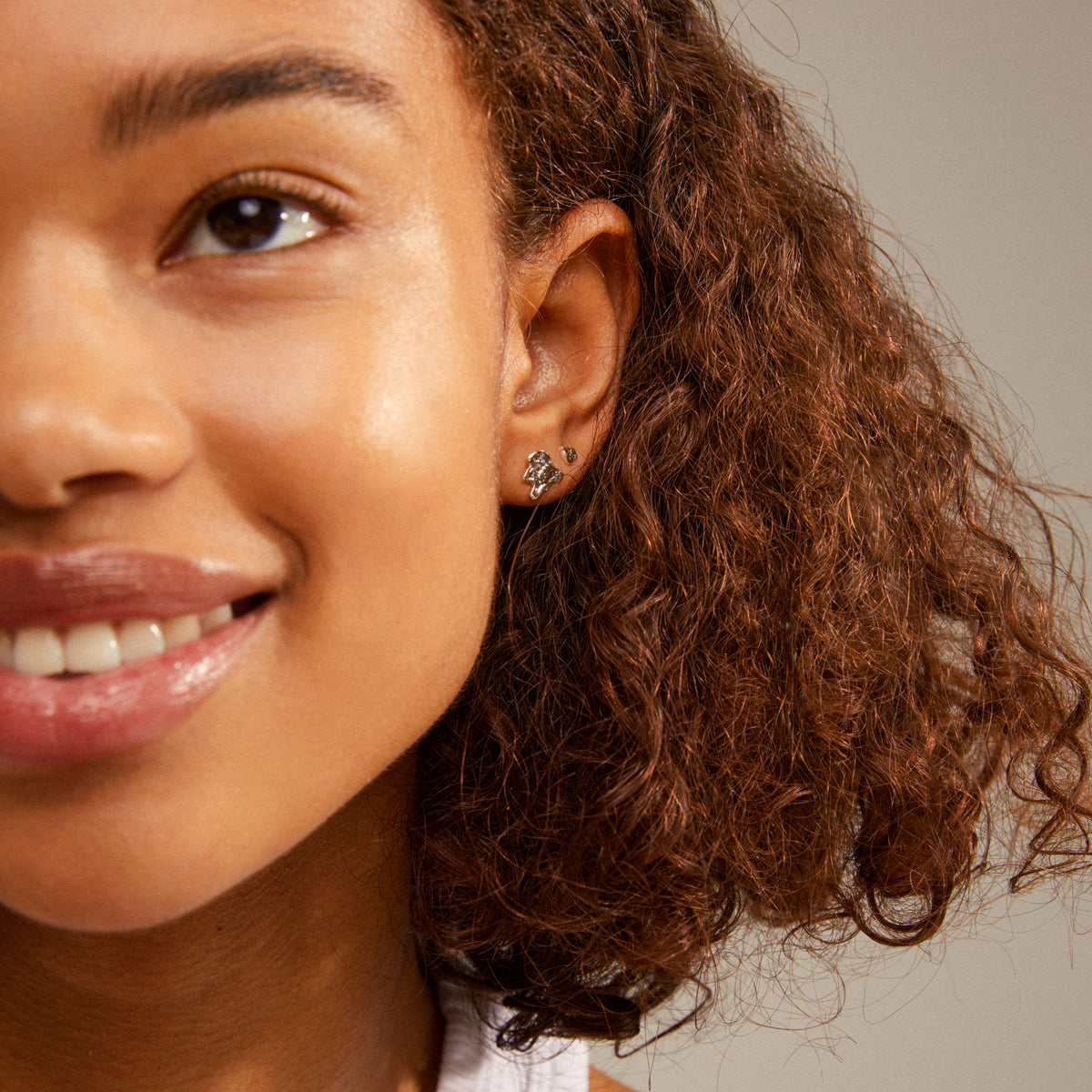 Close-up of a woman's ear adorned with HORIZON silver-plated earrings, showcasing a trendy, mix-and-match ear curation style from Pilgrim.