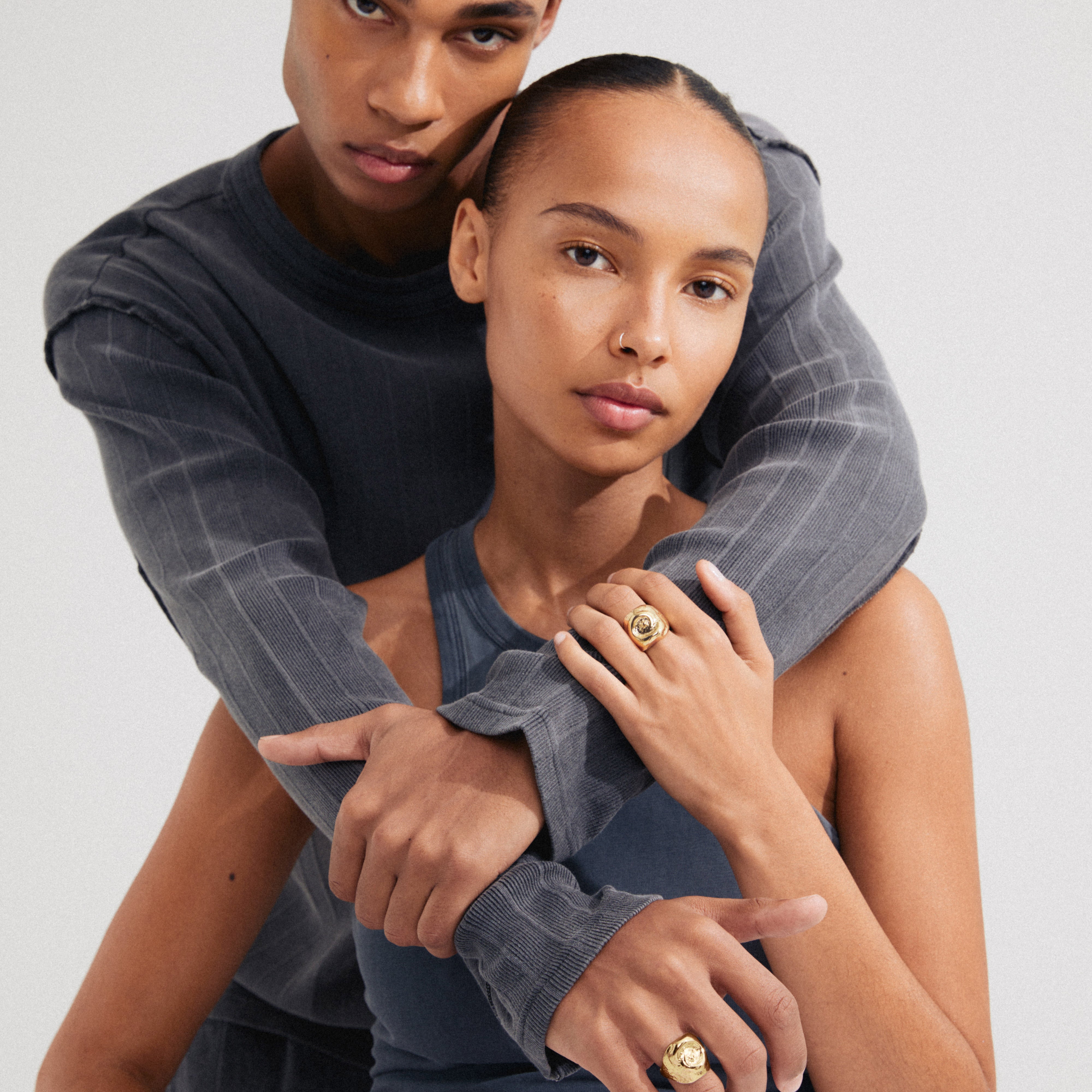 Man and woman displaying Pilgrim's gold-plated SEA ring, featuring a fossil-inspired motif, highlighting personal style and sustainability with 99% recycled material.