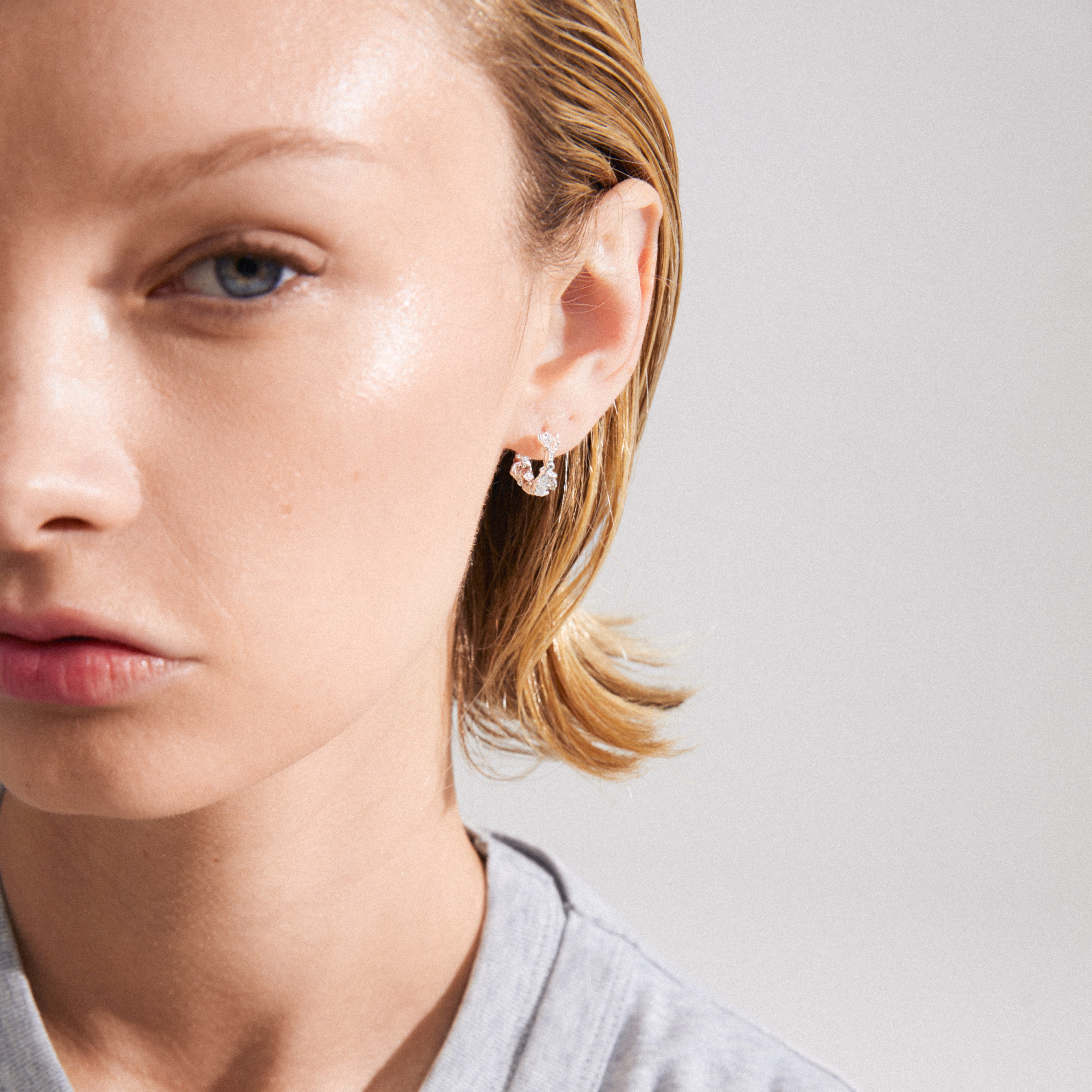 Silver-plated TRUST hoop earrings from Pilgrim, showcasing a close-up of a woman's ear adorned with rustic, handcrafted huggie hoops.