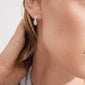 Close-up of an ear adorned with TRUST hoop earrings, silver-plated, showcasing a teardrop design. A hand gently touches the ear, emphasizing the handcrafted elegance.