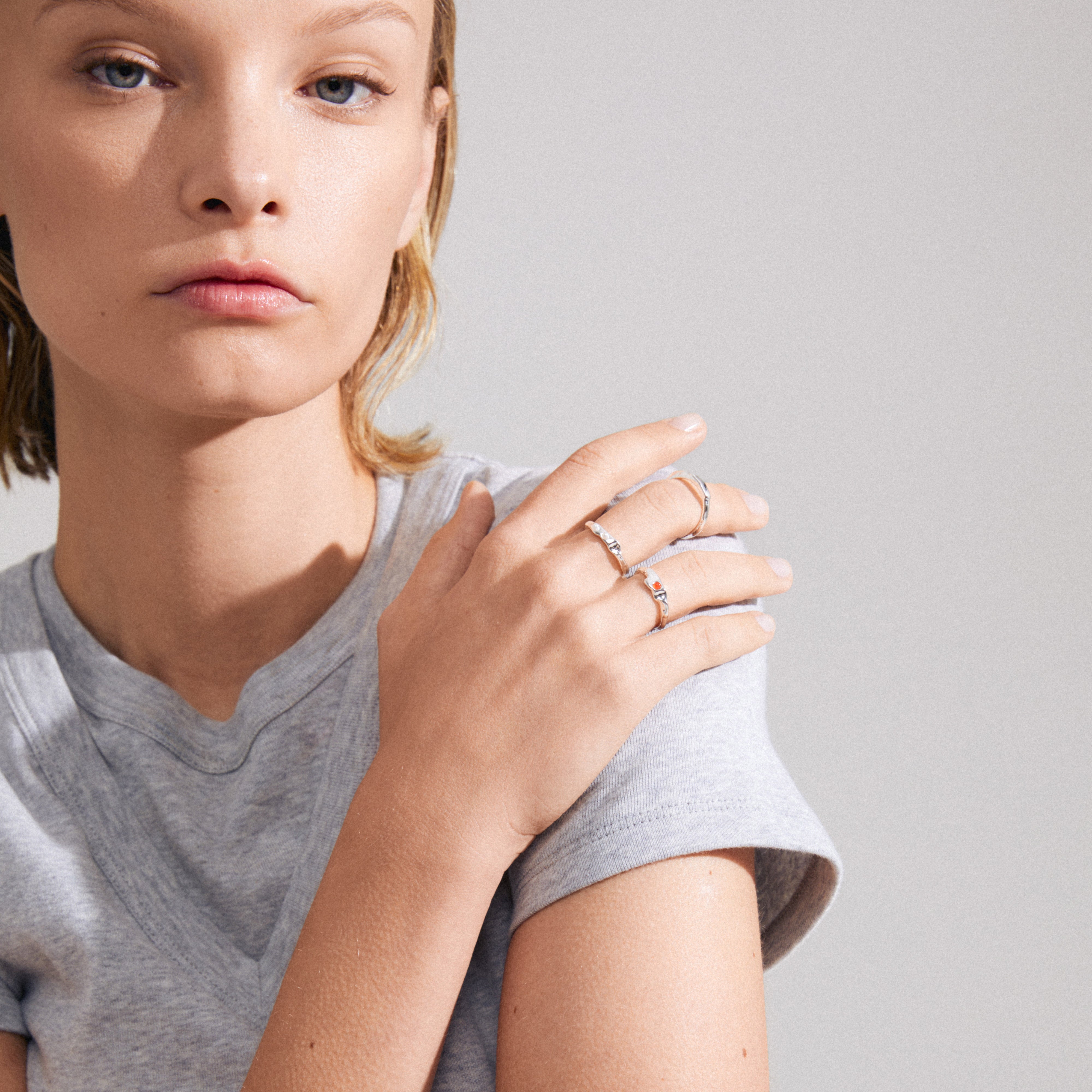 TRUST ring 3-in-1 set silver-plated: Woman wearing a grey shirt, showcasing a close-up of stacked rings featuring a red Agate stone and white glass beads.