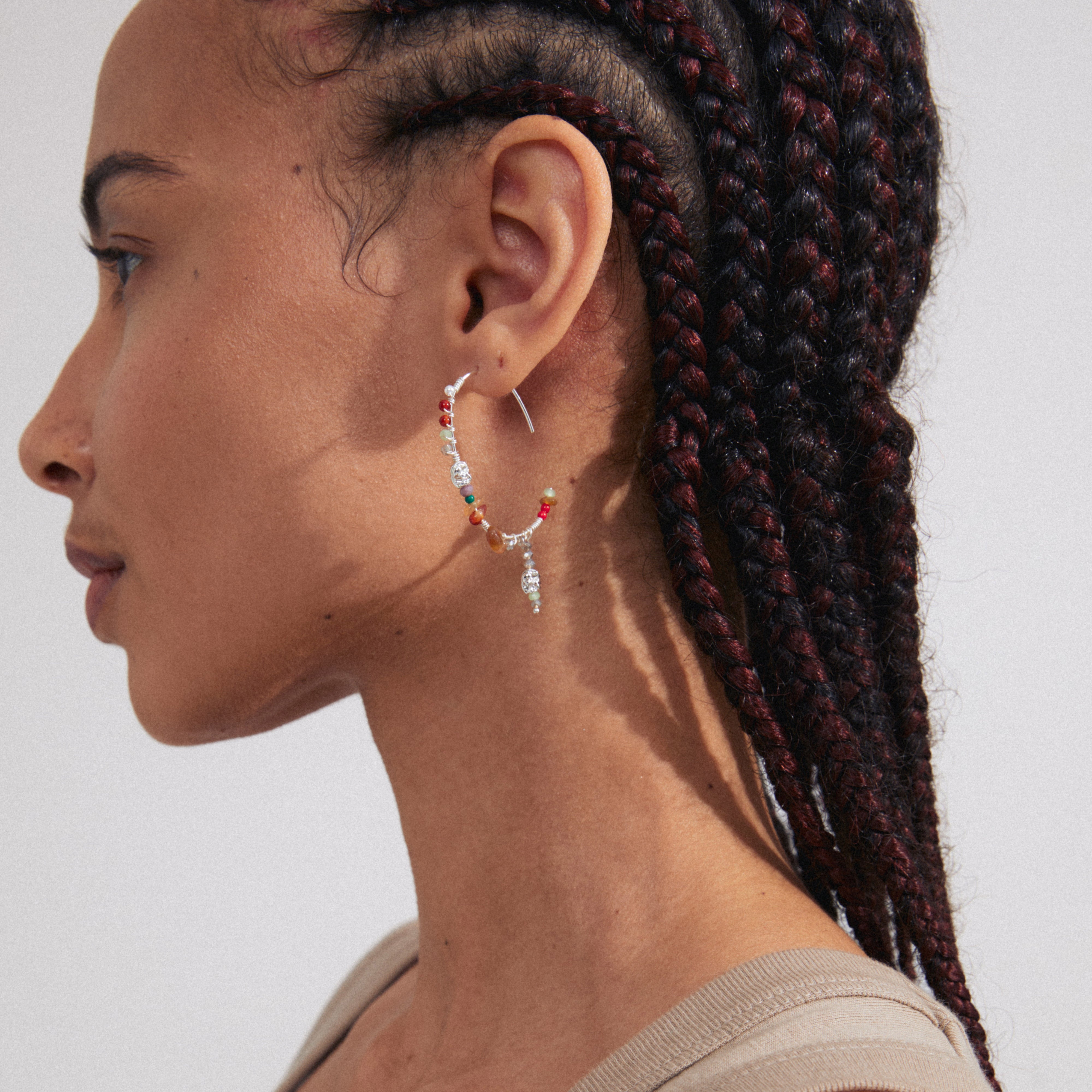 Side view of a woman wearing TRUST half hoop silver-plated earrings with braids, showcasing the earrings' handcrafted bohemian design.