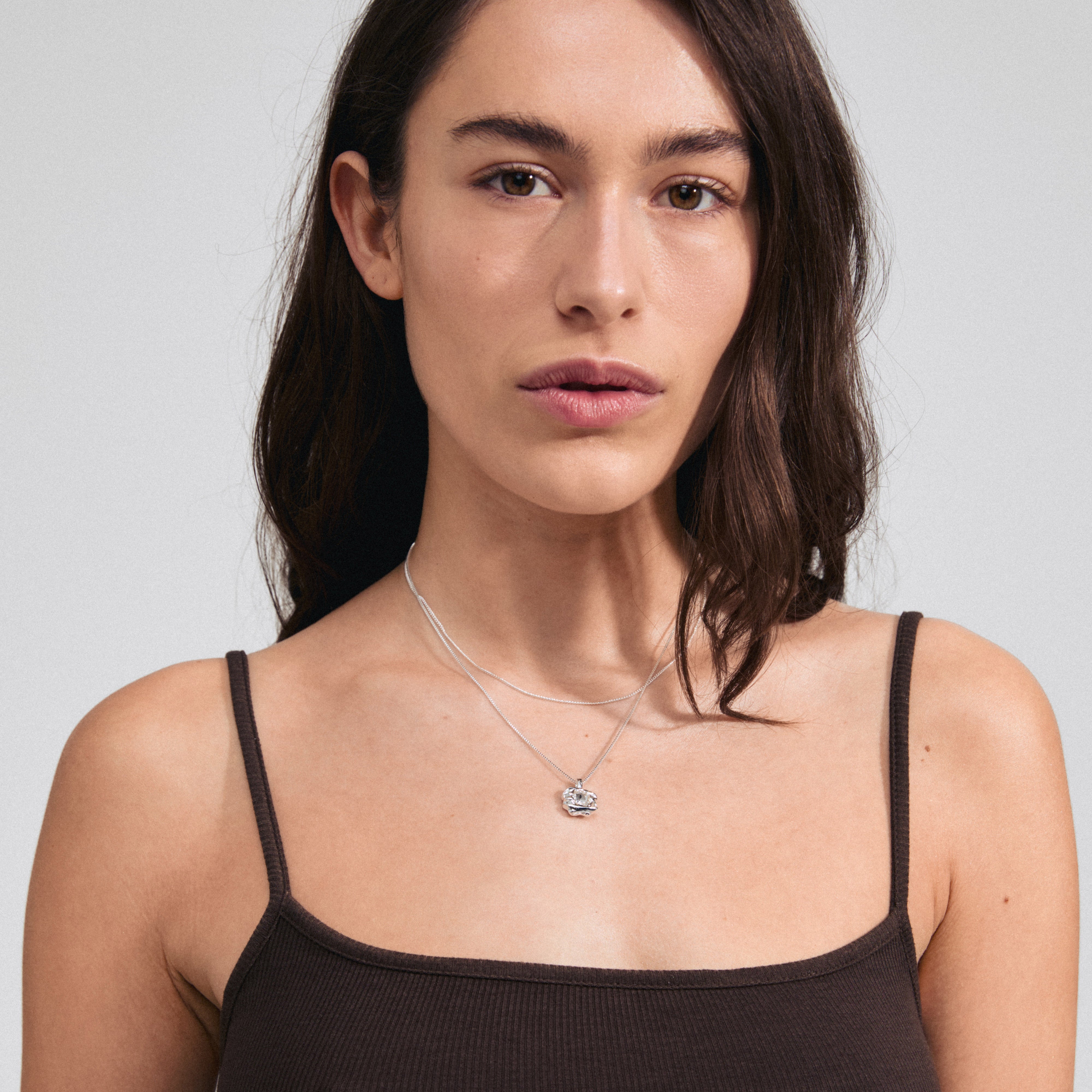 FEEL necklace 2-in-1 set silver-plated featuring a box chain with Preciosa crystal pendant and a slim curb chain, worn by a woman with long brown hair.